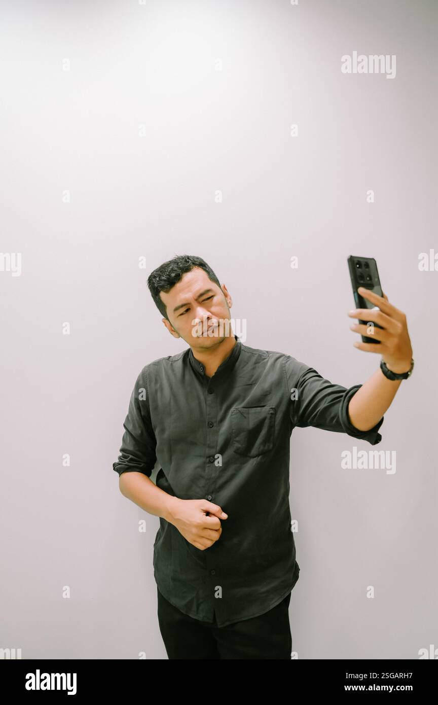 Ein junger Mann macht ein Selfie, um einen Moment mit seinem Smartphone festzuhalten. Stockfoto