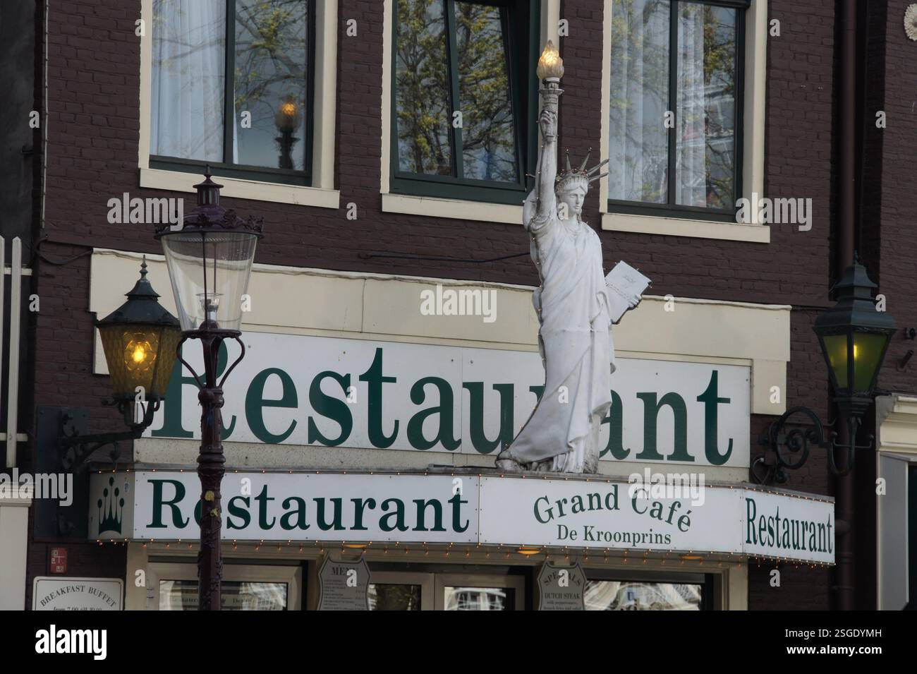 Ein Restaurant in Amsterdam mit einer überraschenden amerikanischen Note: Eine Nachbildung der Freiheitsstatue steht stolz darauf und wirbt für Frühstück. Könnte das sein Stockfoto