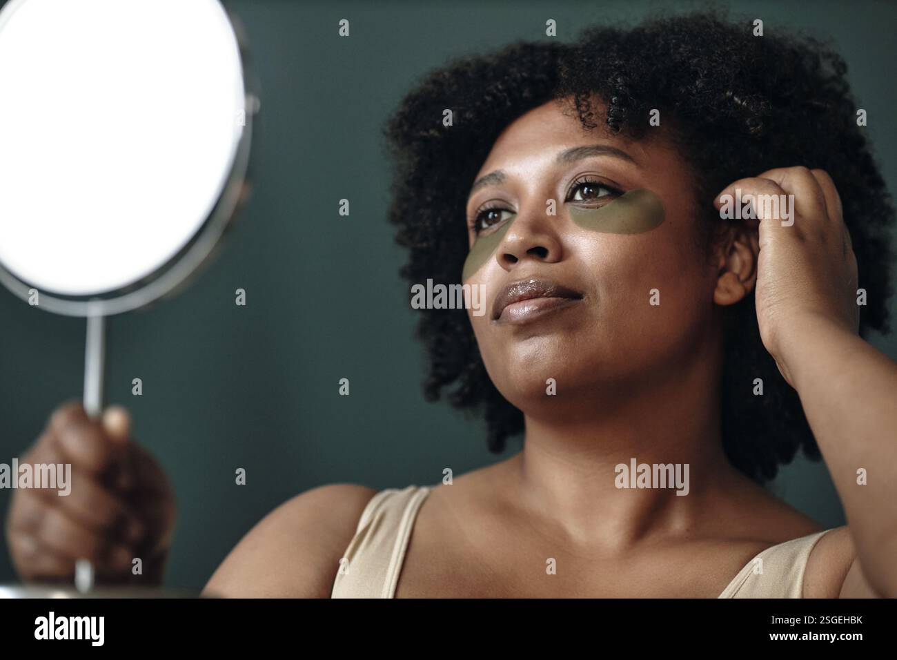 Porträt einer Frau, die Gesichtsmaske Creme mit Spiegel aufträgt Stockfoto