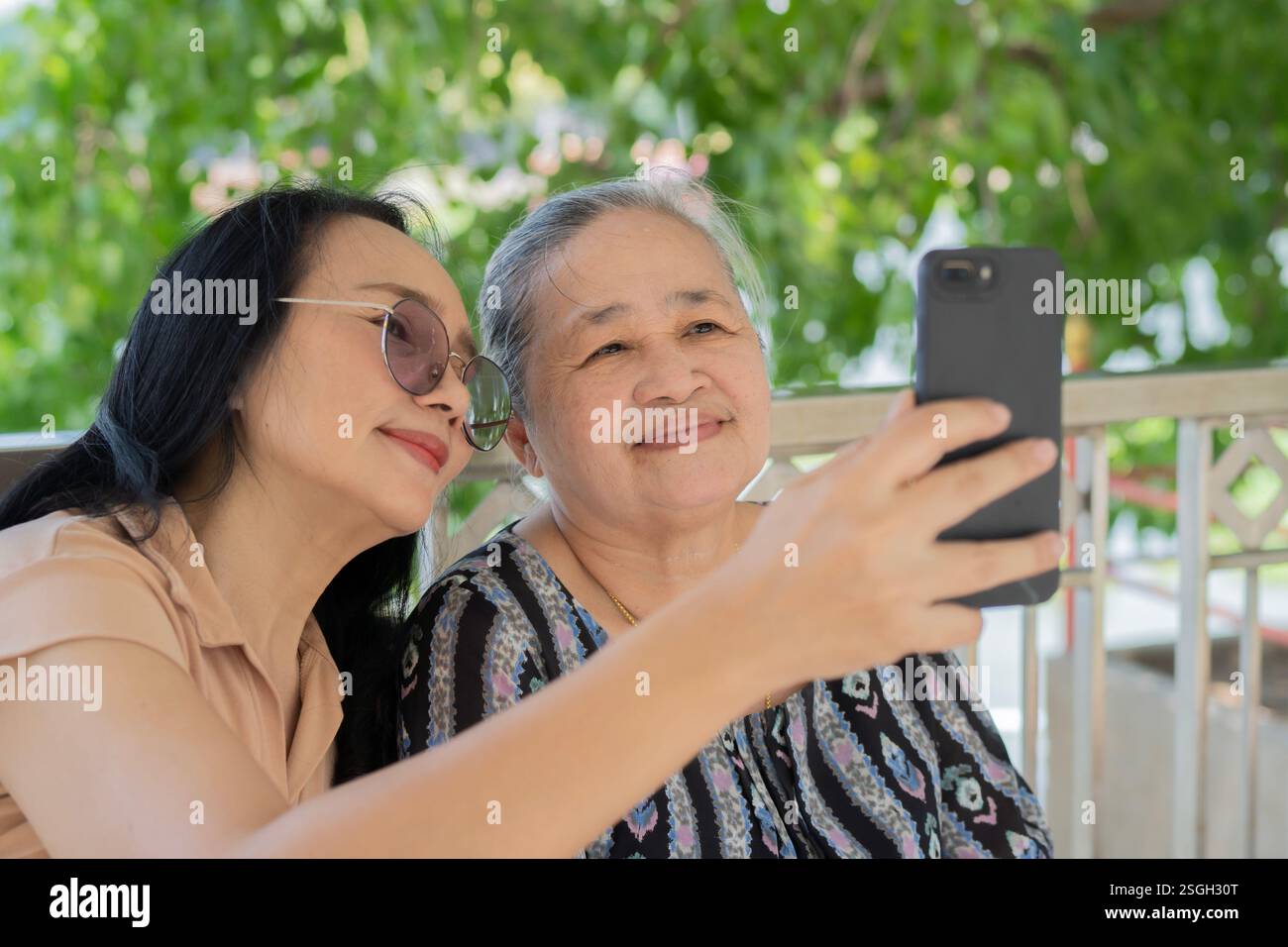 Asiatische Seniorinnen und Töchter, die Fotos mit dem Handy machen. Selektiver Fokus. Stockfoto