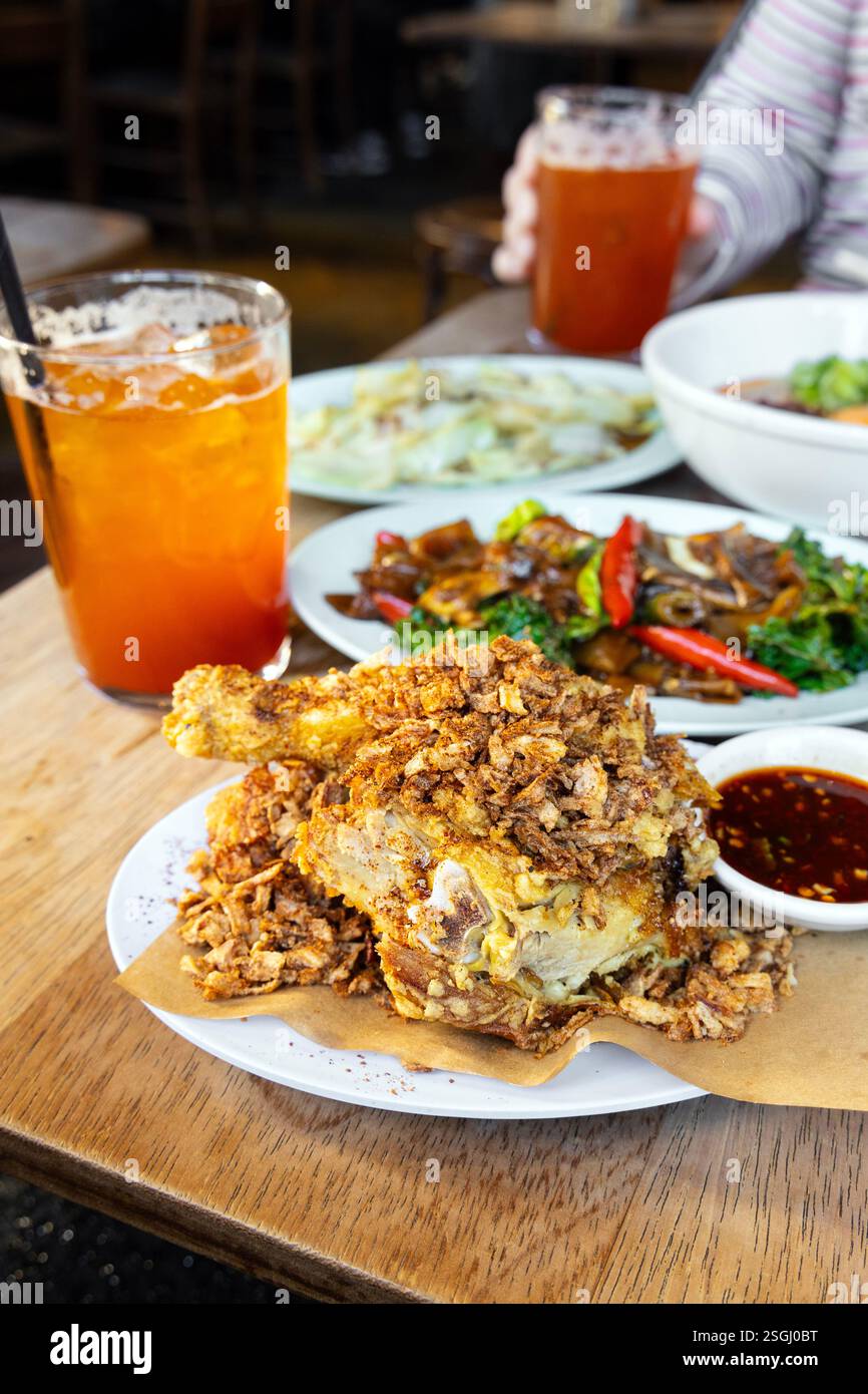 Gebratenes Hühnchen und thailändischer Eistee im Smoking Goat, Shoreditch, London, England Stockfoto