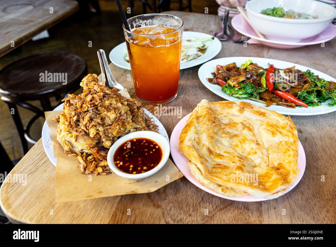 Gebratenes Huhn, Roti, Pad See Yew mit Nameko-Pilzen und Thai Iced Tea im Smoking Goat, Shoreditch, London, England Stockfoto