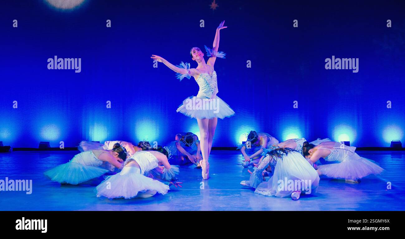 Ballerina, die in einem blau beleuchteten Theater mit Tänzern in der Mitte der Bühne posierte. Der Nussknacker, Bainbridge Island, USA Stockfoto