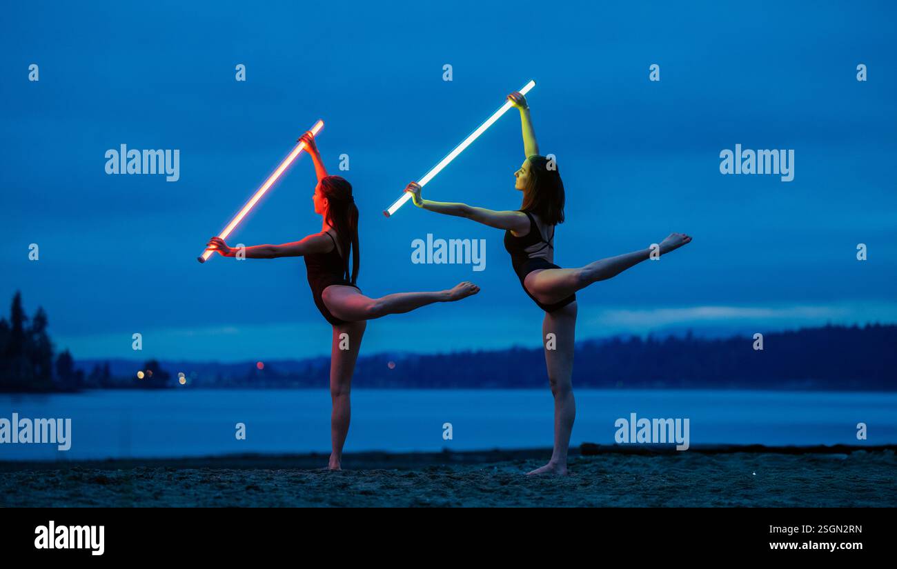 Zwei Tänzer am Strand erleuchten den Nachthimmel mit leuchtenden Säbelsäbeln, USA Stockfoto