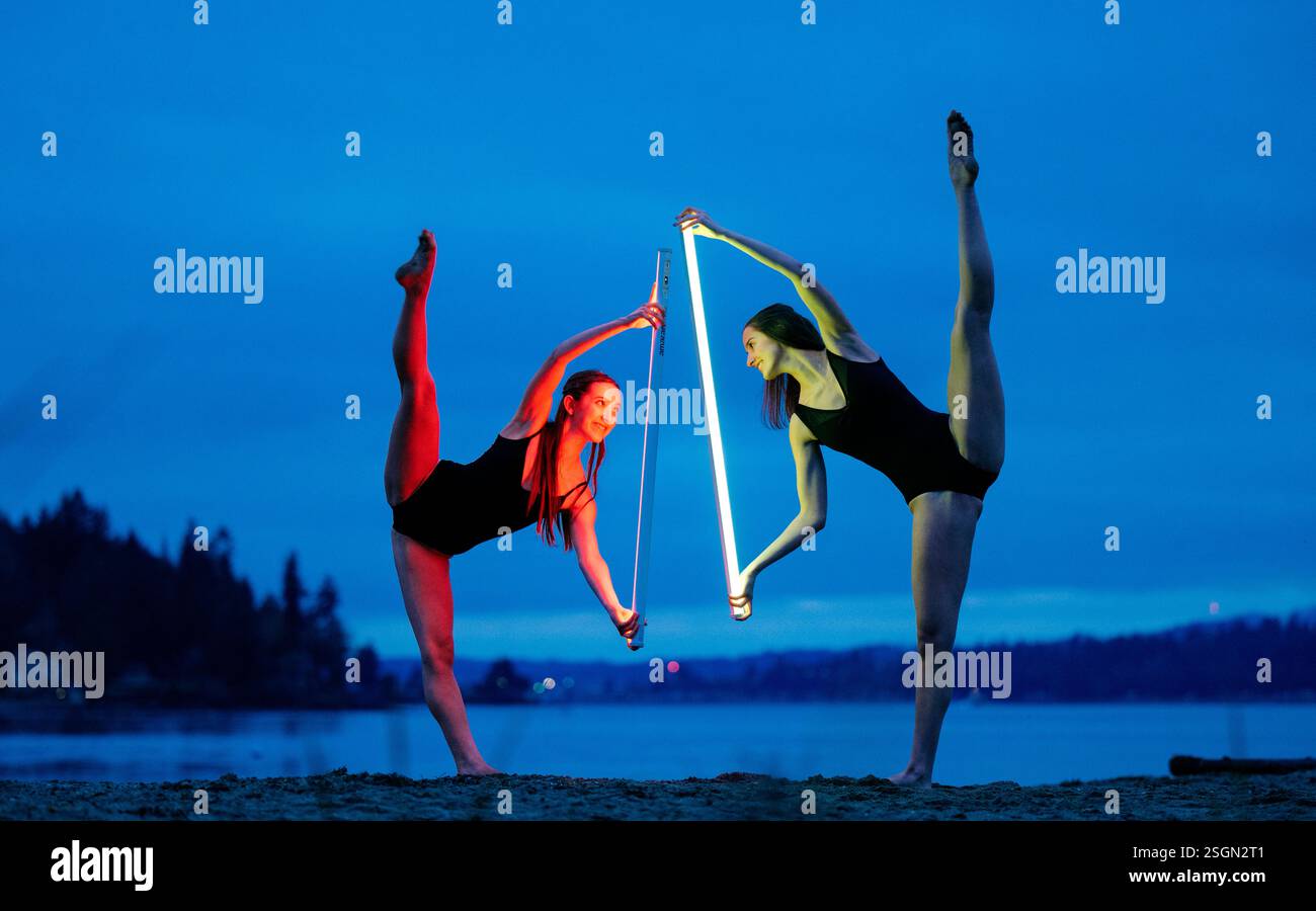 Zwei Tänzer mit leichten Säbeln treten an einem Strand in der Abenddämmerung vor blauem Himmel auf, USA Stockfoto