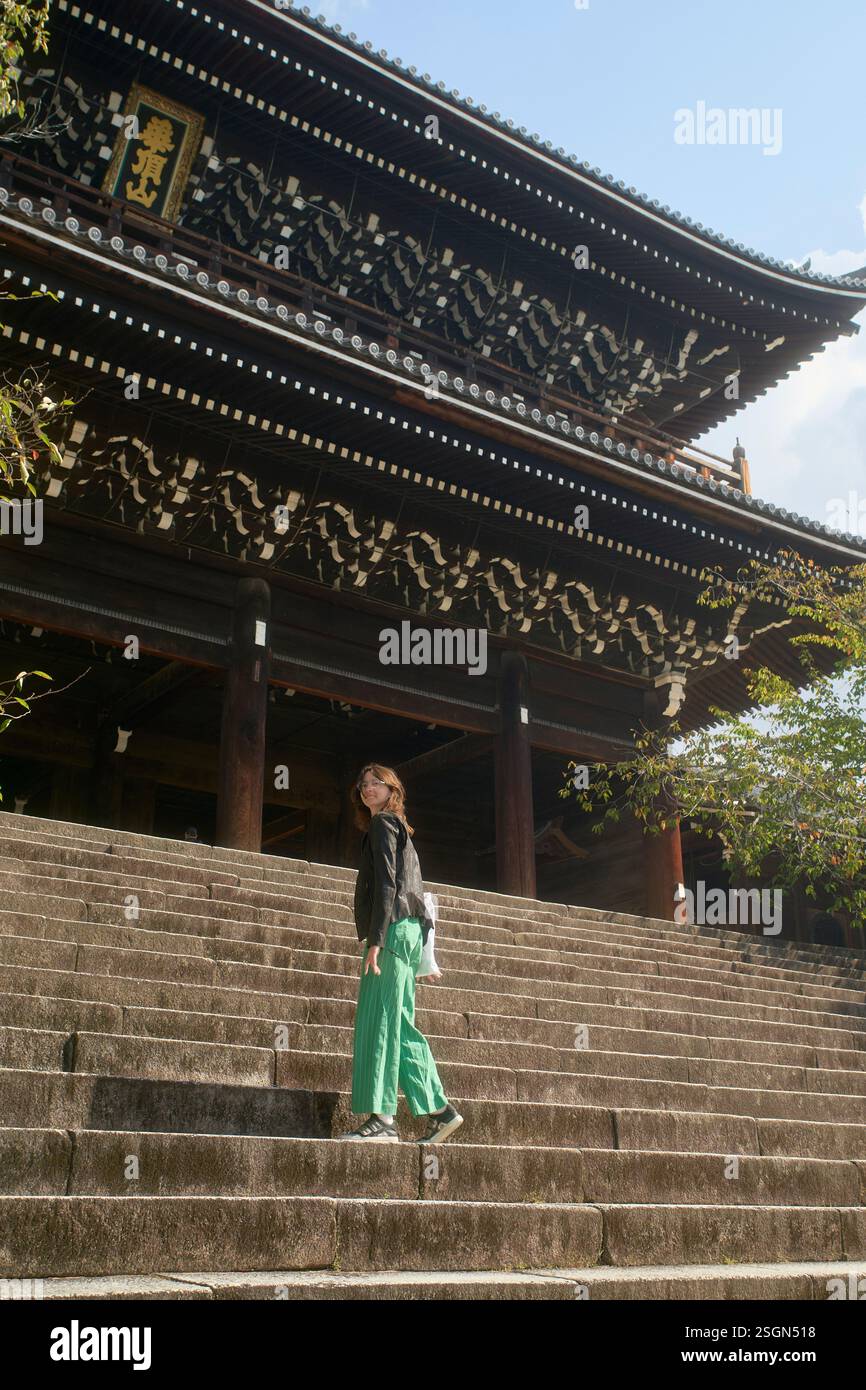 Frau, die Steintreppen in Richtung eines traditionellen japanischen Tempels geht. Kyoto, Japan Stockfoto