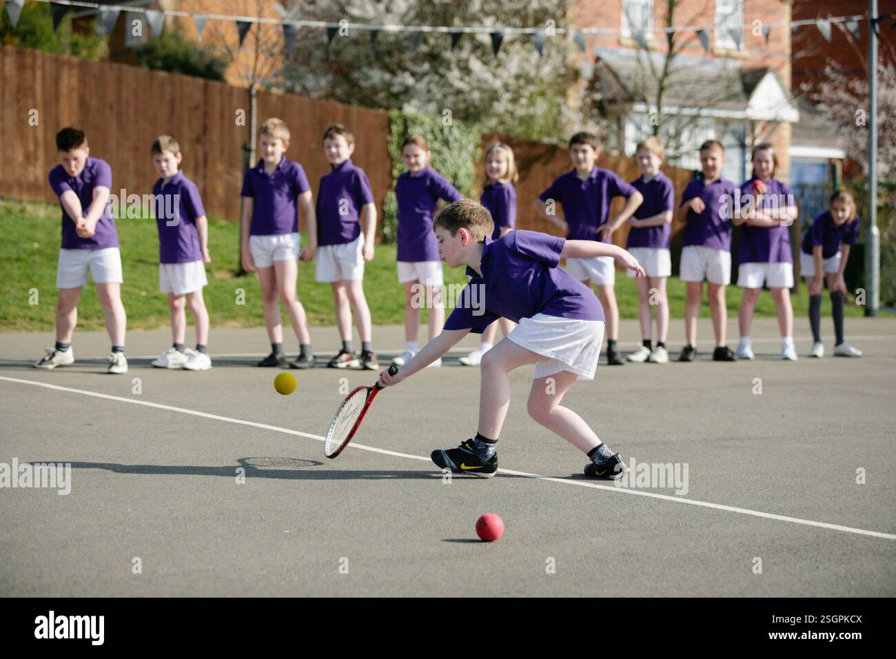 Kinder, die eine Tennisstunde auf einem Schulspielplatz in Großbritannien haben. Stockfoto