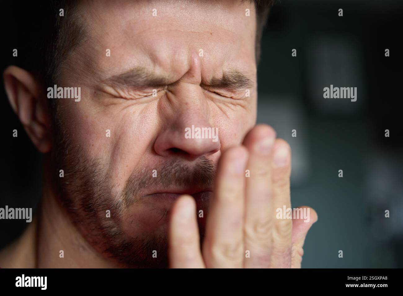 Schlechter Atem aus dem Mund. Nahaufnahme eines Mannes, der seinen Atem überprüft, indem er in seine Hand ausatmet, und zeigt Bedenken über Mundhygiene oder schlechten Atem Stockfoto