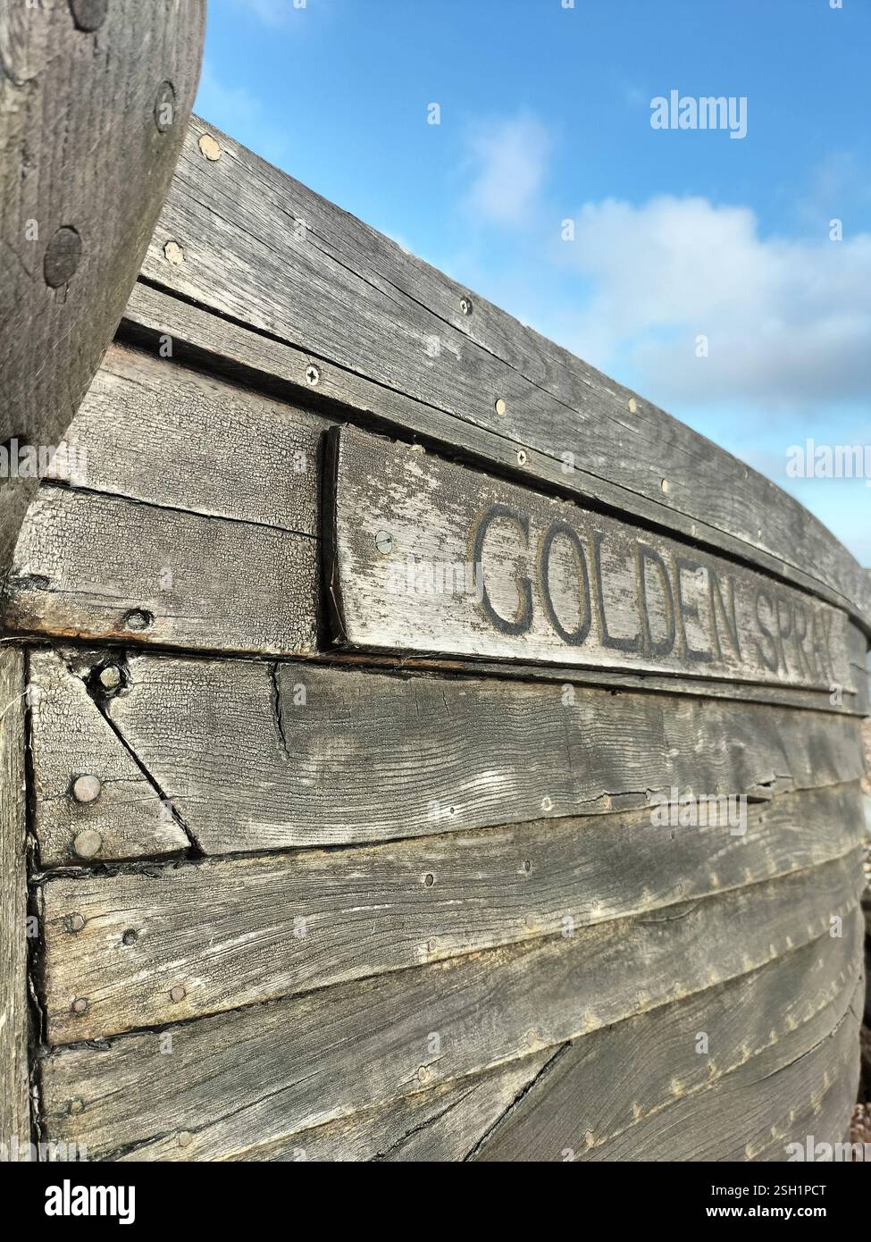 Aus nächster Nähe ein rustikales Holzschild mit den Worten Golden Spring. Das Schild ist verwittert und zeigt seine alte Textur. - Smartphone-aufgenommenes Stockfoto