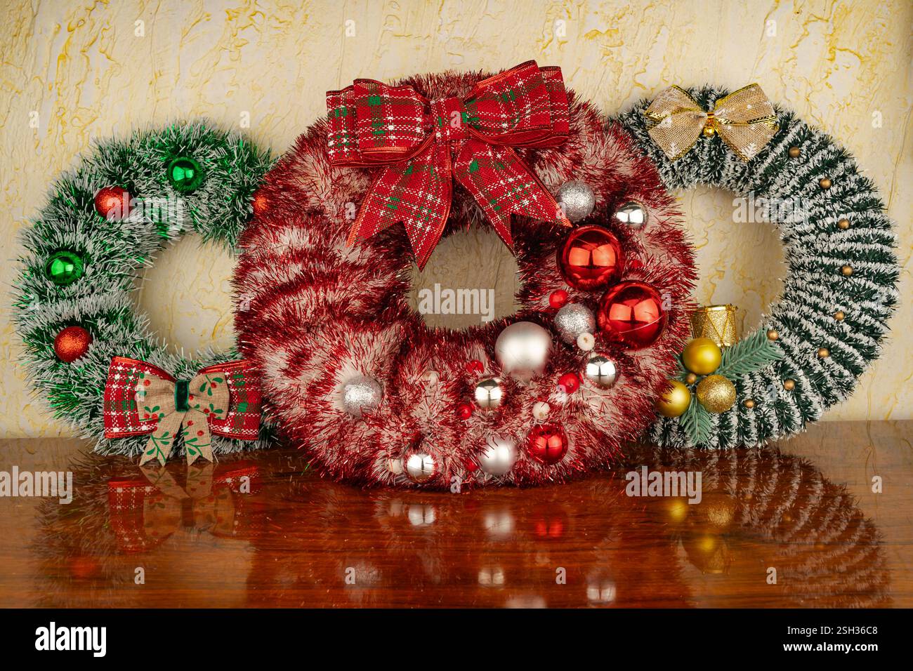 Üppiger Nadelkranz aus Kiefer mit roten Beeren an der Wand. Eine wunderschöne Dekoration, die Freude, Komfort und Familientraditionen symbolisiert. Stockfoto