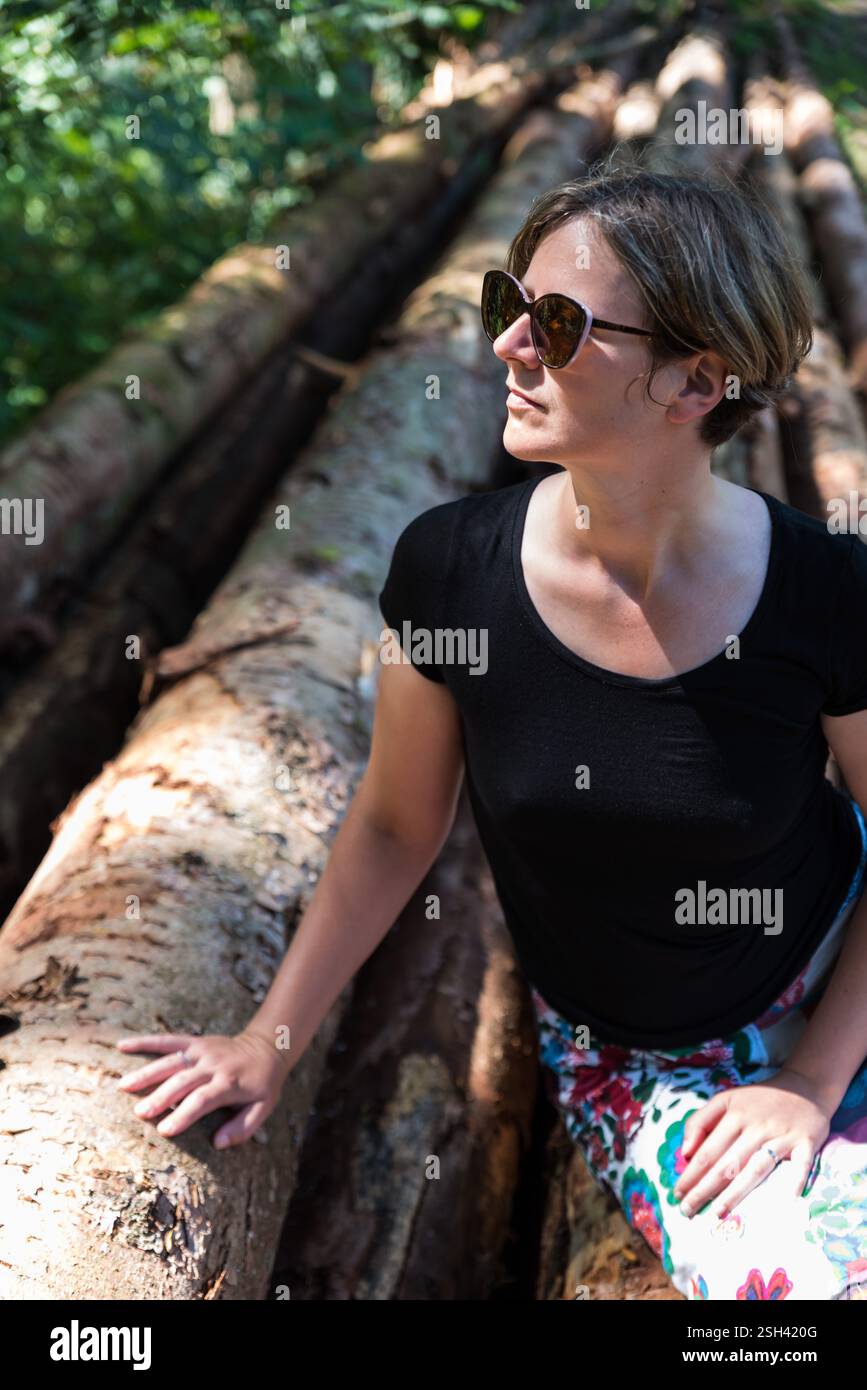 Porträt einer aktiven 36-Jährigen Frau, die auf Baumstämmen im Wald sitzt, Burg-Reuland, Belgien Modell veröffentlicht Stockfoto