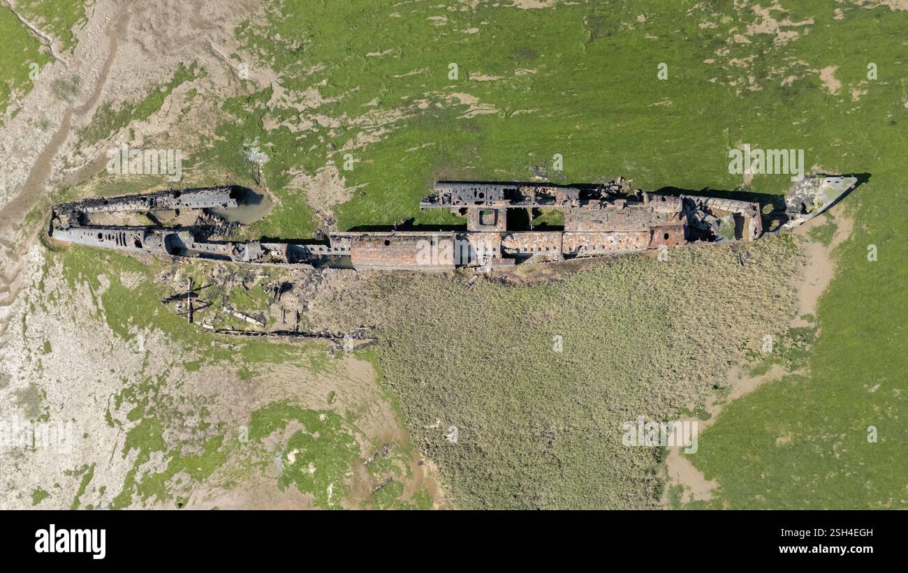 Aus der Vogelperspektive eines deutschen UBoat-Schiffswracks, das teilweise in grünes Grasland getaucht ist, zeigt die Überreste des Schiffes mit rostigem Metall und gebrochenem Stru Stockfoto
