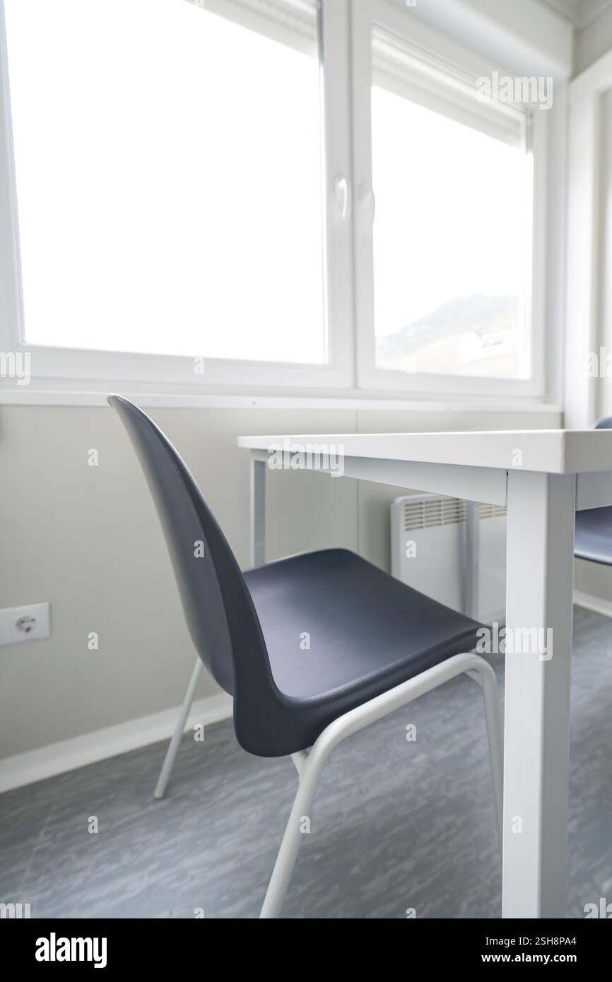 Helles Zimmer mit einem einfachen Tisch und Stuhl, Fenster im Hintergrund, Flüchtlingsunterkunft Beermiss, Calmbach, Schwarzwald, Deutschland, Europa Stockfoto