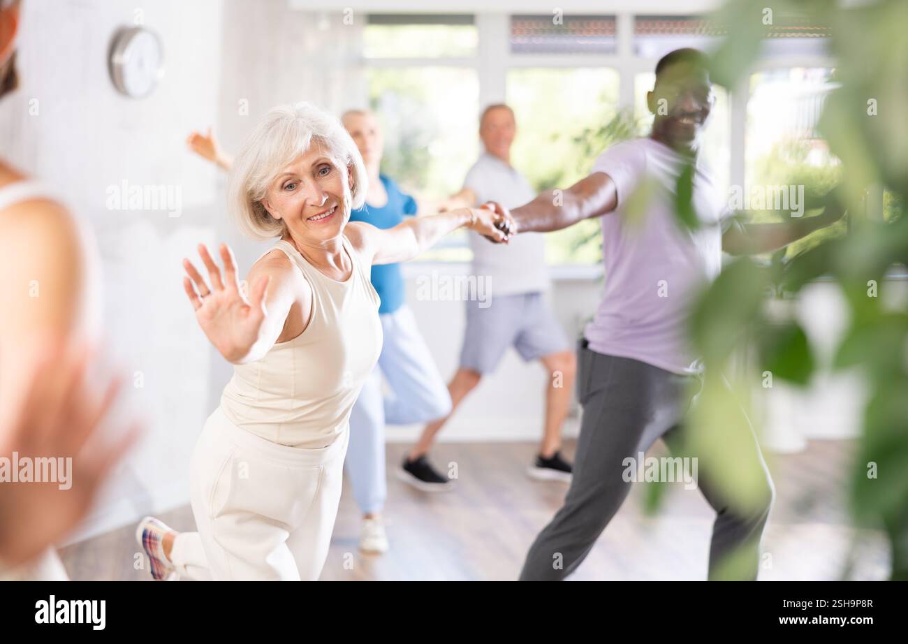 Ältere Frau, die lindy-Hop-Umzüge mit afroamerikanischem Partner praktiziert Stockfoto