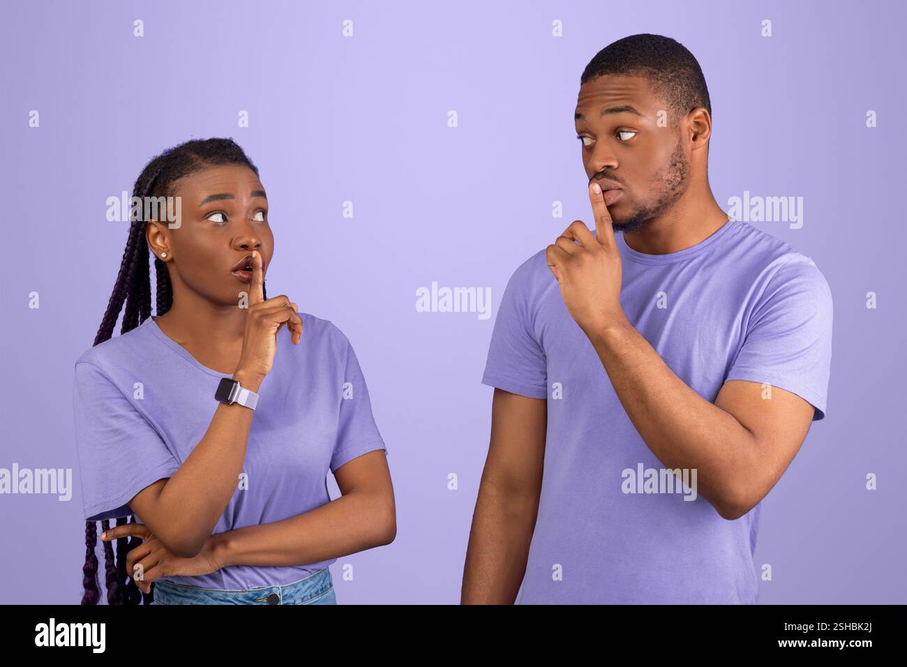 Schwarzes Paar, das Finger auf die Lippen stampft und ein Zeichen für die Stille macht Stockfoto