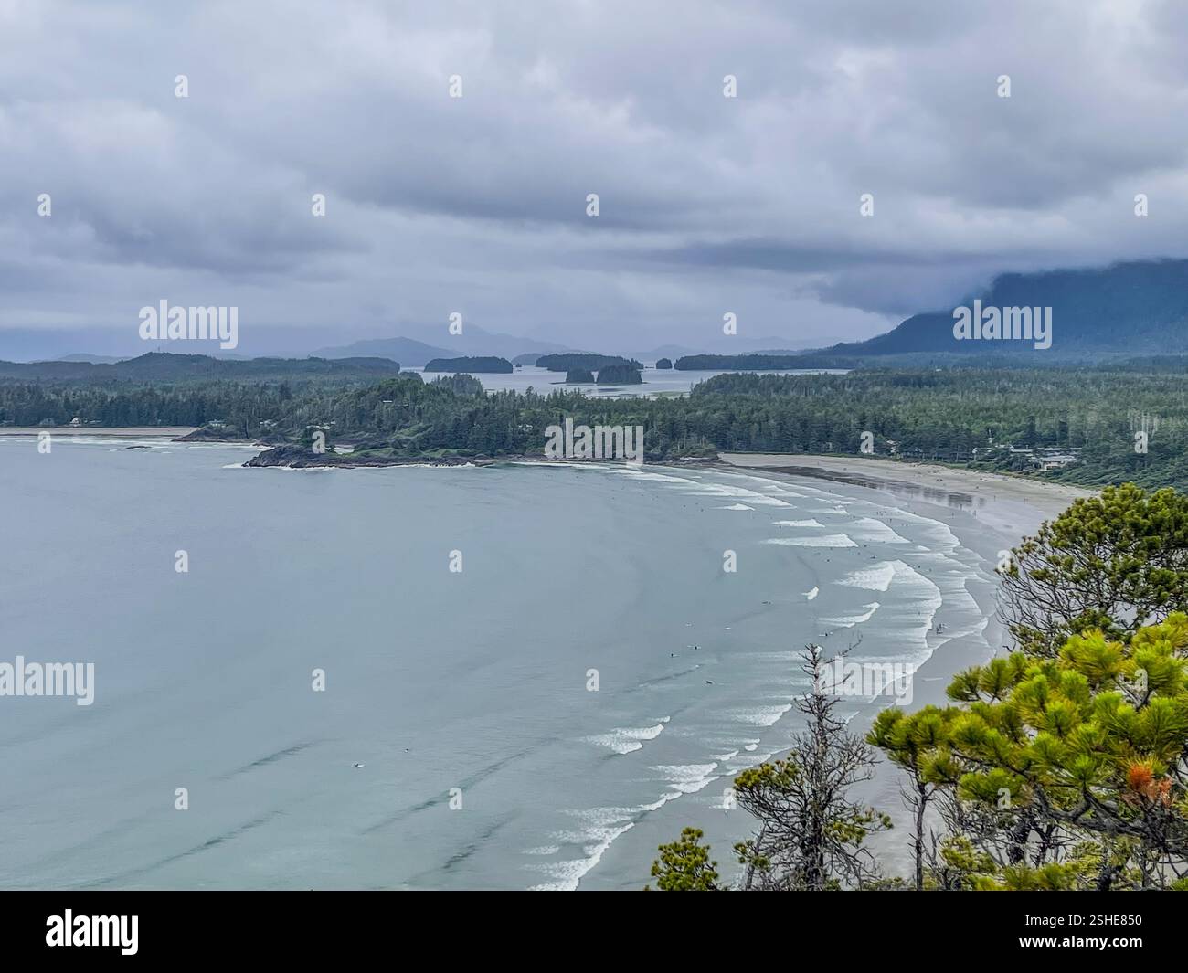 Malerische Küstenlandschaft mit Wald, Strand und bewölktem Himmel. Perfekt für Reisen und Naturthemen. - Smartphone-aufgenommenes Stockfoto