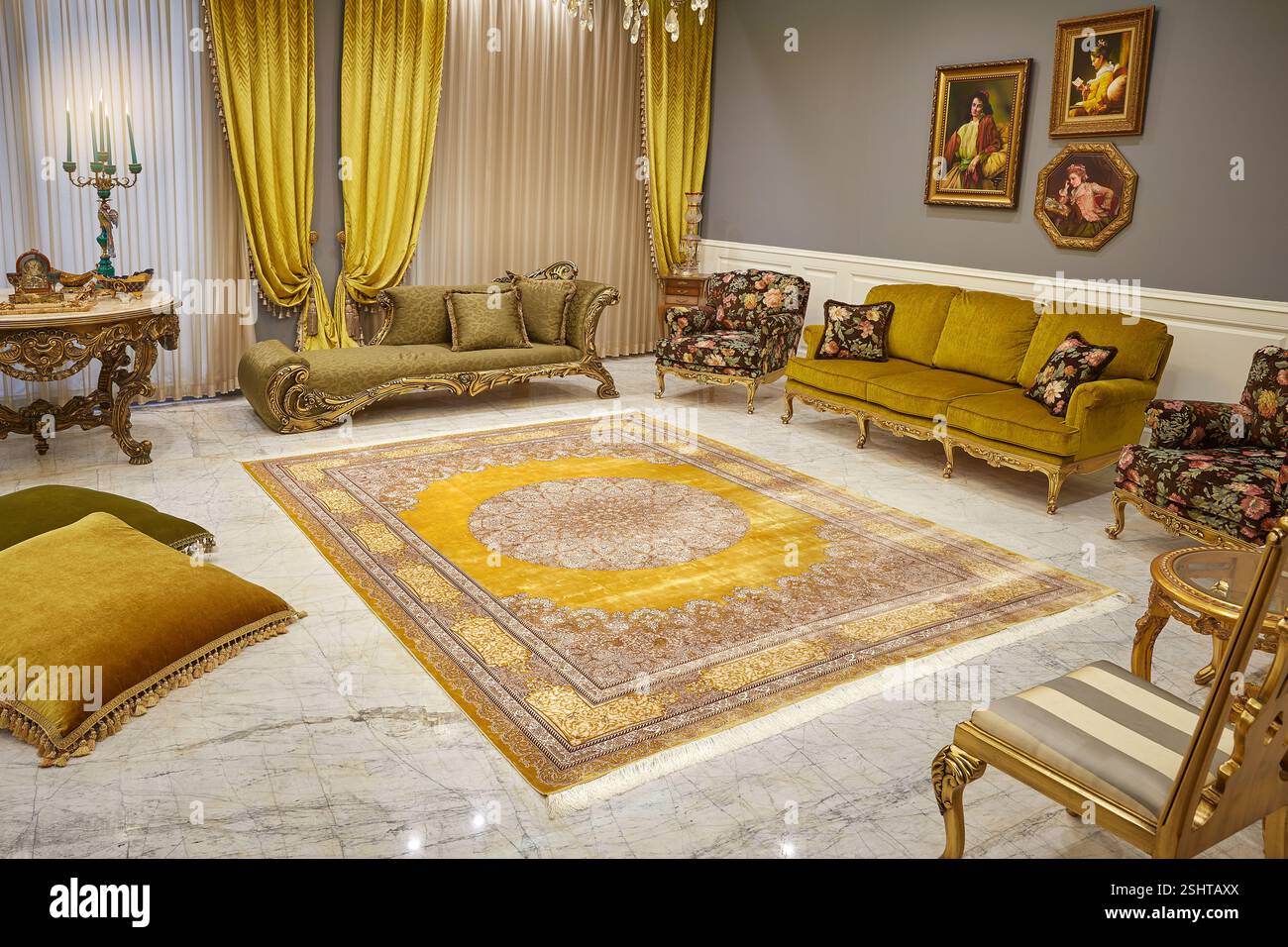 Verziertes Wohnzimmer mit goldenem persischem Teppich, antiken Möbeln und luxuriösen goldenen Vorhängen auf Marmorboden. Stockfoto
