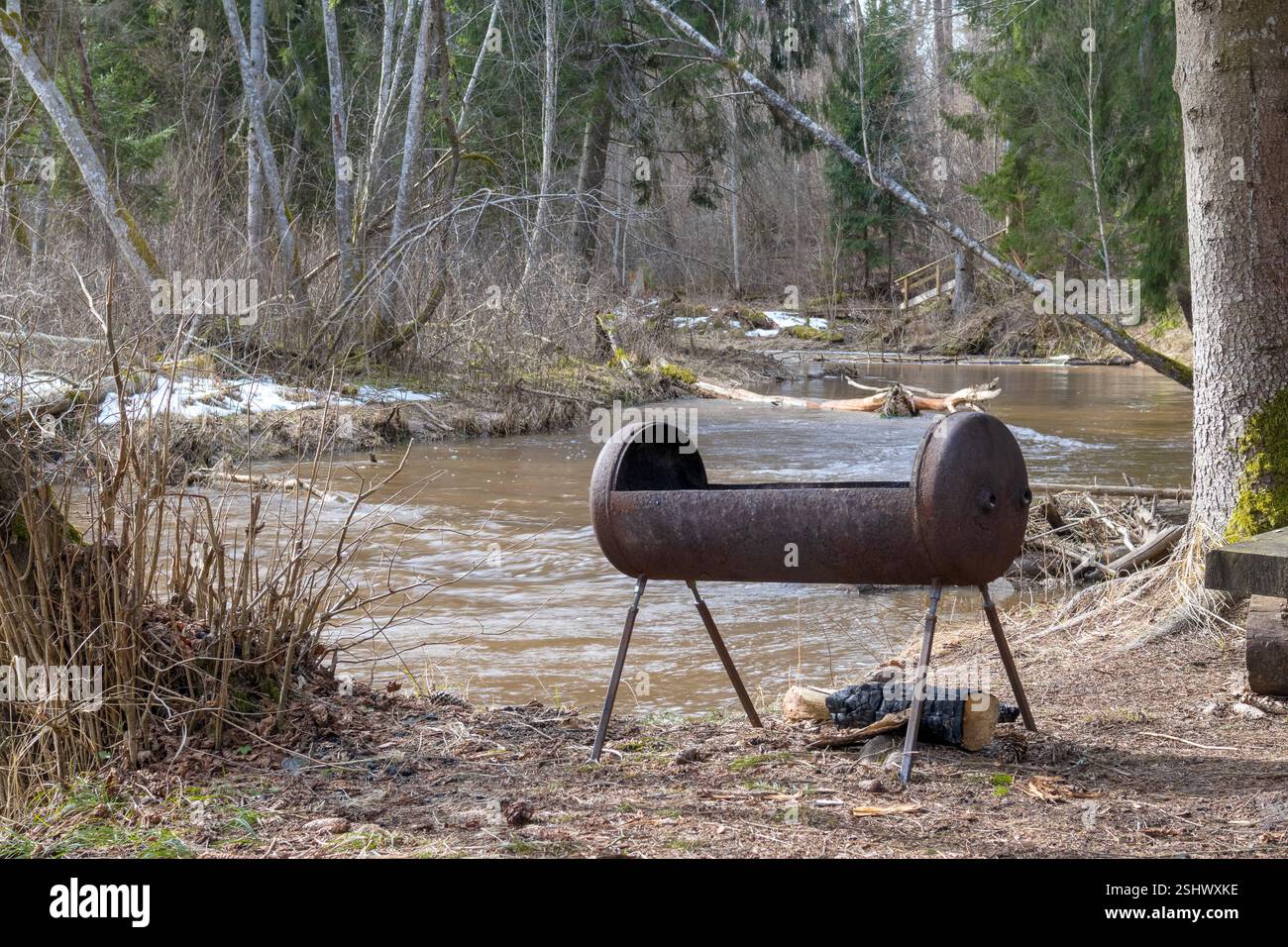 Ein malerischer Blick auf den Wald mit einem Fluss, der durch ihn fließt, und einem Barbecue am Fluss. Stockfoto