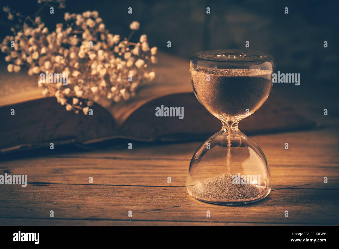 Sanduhr mit altem Buch. Symbol für vergangene Zeit und Erinnerungen. Konzeptionelles Vintage-Image Stockfoto