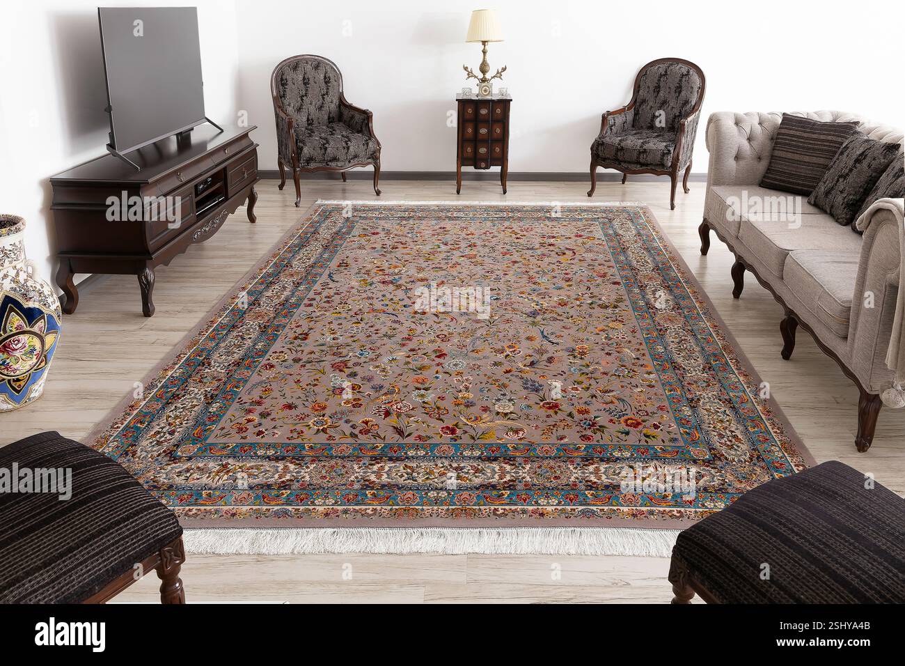 Gemütlicher Innenraum mit hellem, traditionellem Teppich, bequemen Stühlen und natürlichem Licht Stockfoto