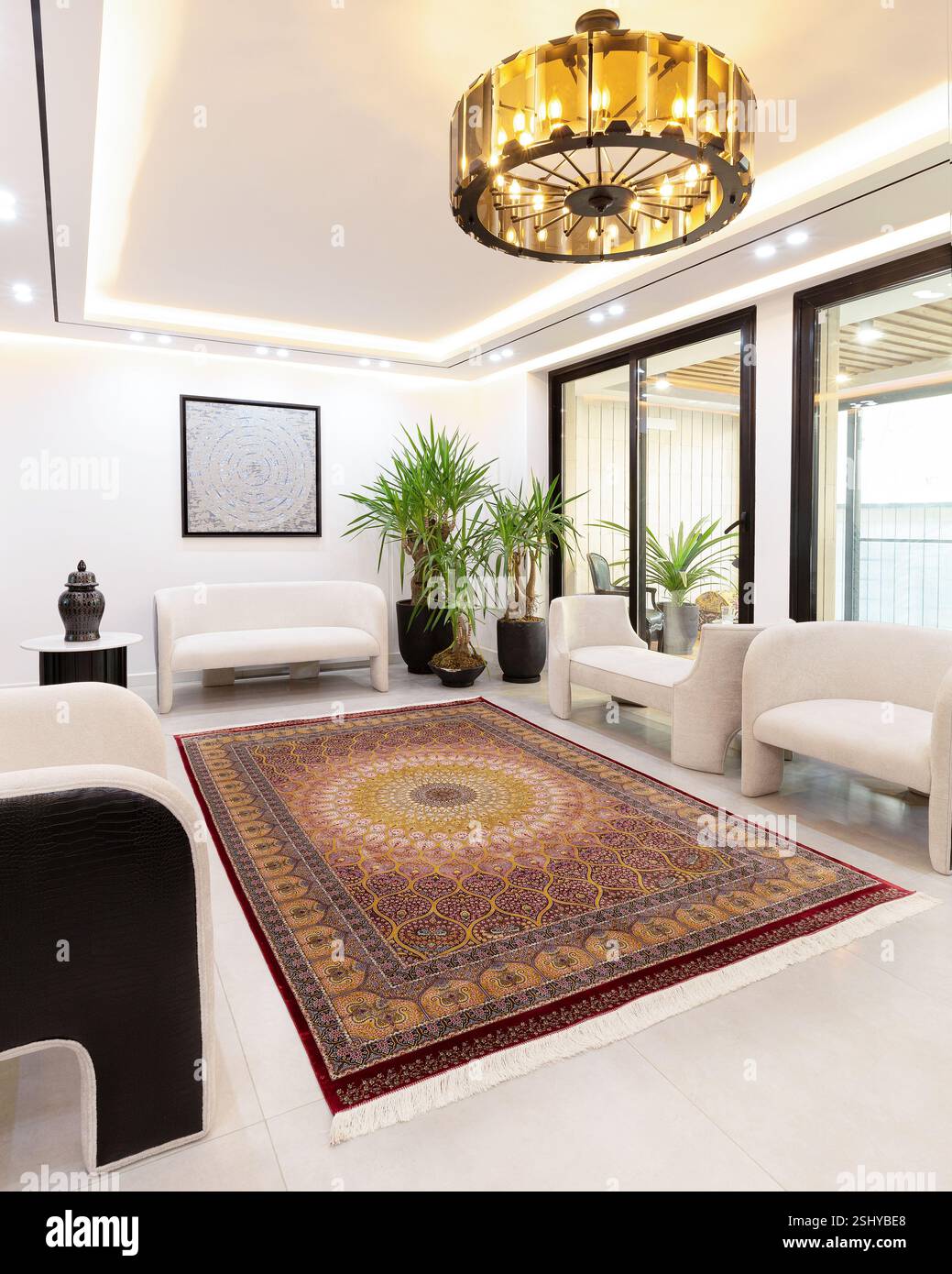 Helles und luftiges Wohnzimmer mit einem traditionellen roten und orangen Teppich. Stockfoto