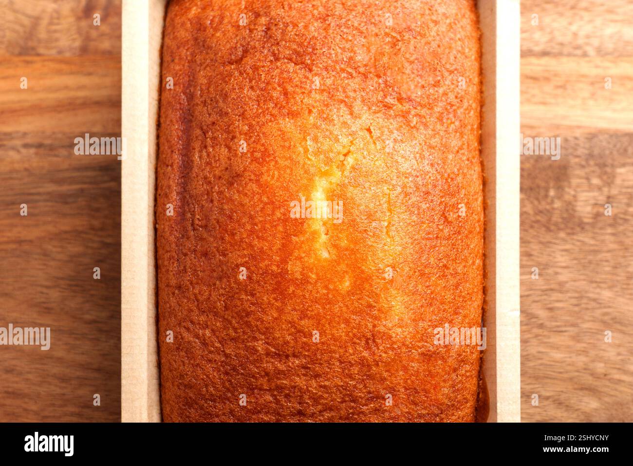Frisch gebackener spanischer Zitronenschwamm in einer biologisch abbaubaren Papierschale auf einer Holzoberfläche. Traditionelles mediterranes Dessert. Draufsicht Stockfoto