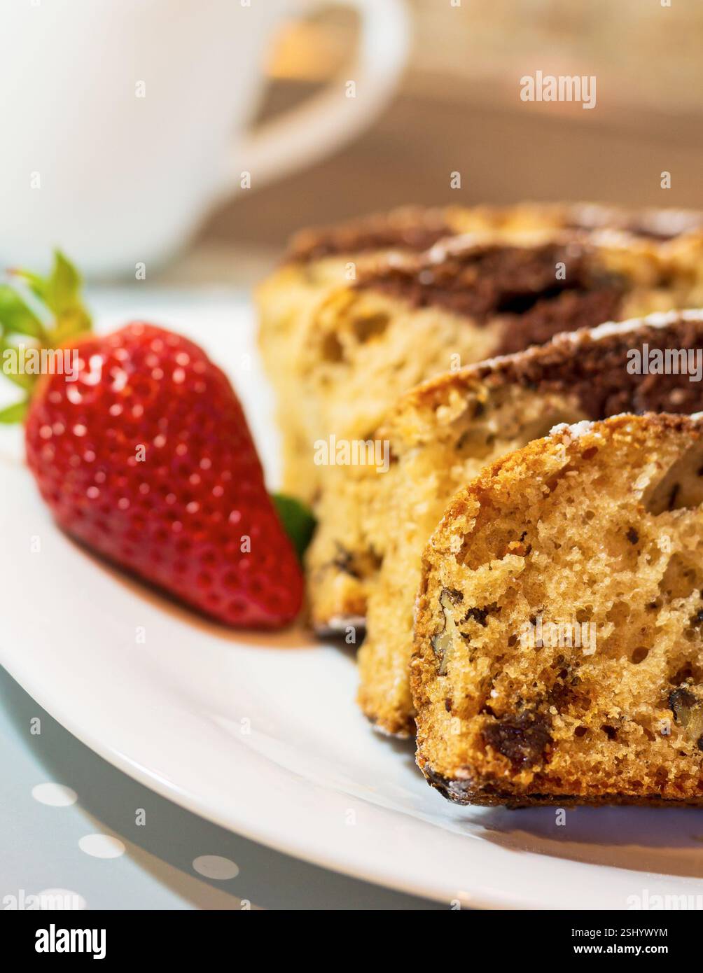 Marmorkuchen mit Rosinen und Walnüssen. Ein Stück Kuchen auf einem Teller mit einer Erdbeere. Stockfoto