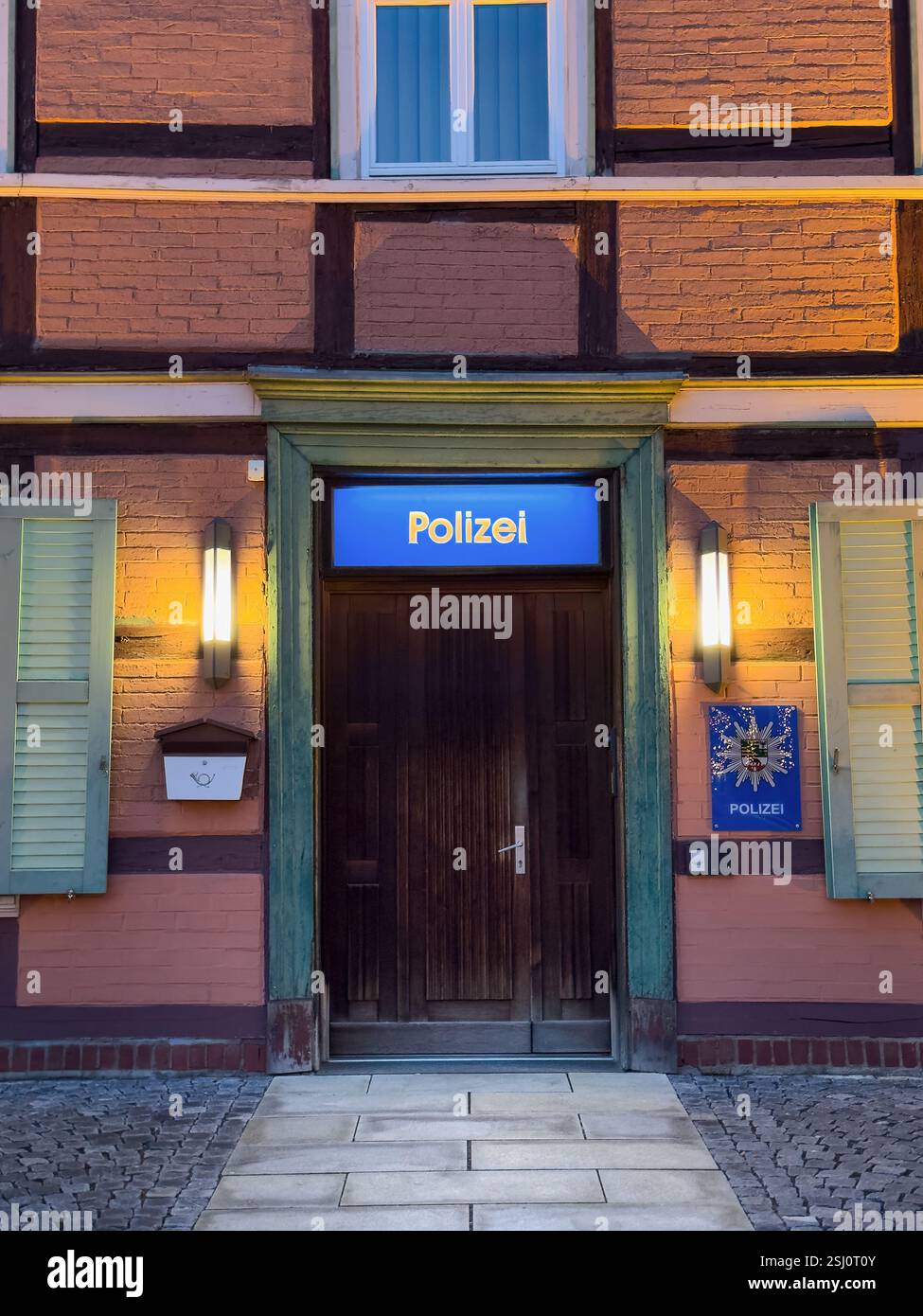 Polizeiwache in Wernigerode, Sachsen-Anhalt. Historisches Fachwerkgebäude im Harz, beleuchtet nach Sonnenuntergang. - Smartphone-aufgenommenes Stockfoto