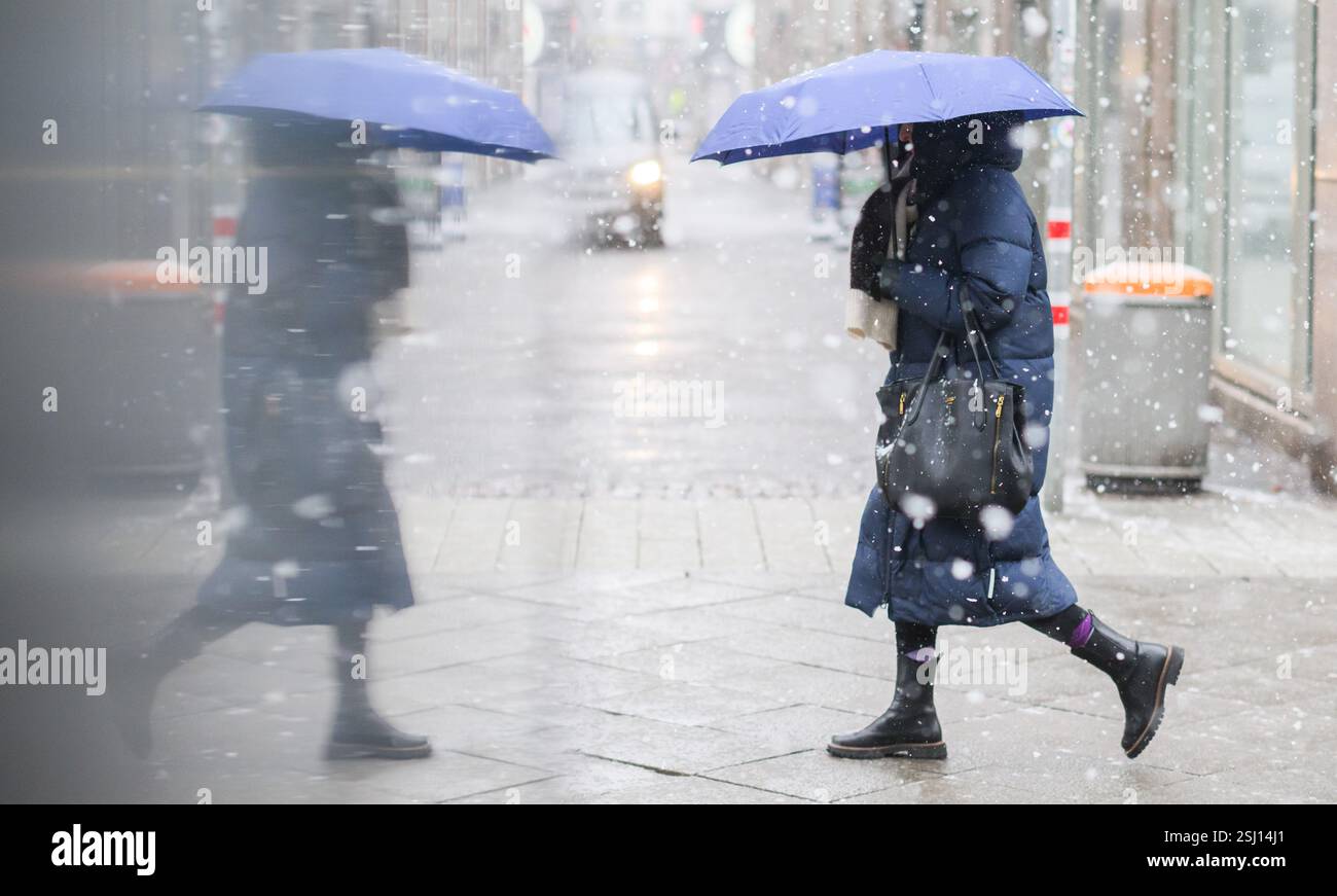 Hannover, Deutschland. Februar 2025. Eine Frau mit einem Regenschirm wird während des Schneefalls in der Glasscheibe eines Vitrinenregals reflektiert. Quelle: Julian Stratenschulte/dpa/Alamy Live News Stockfoto