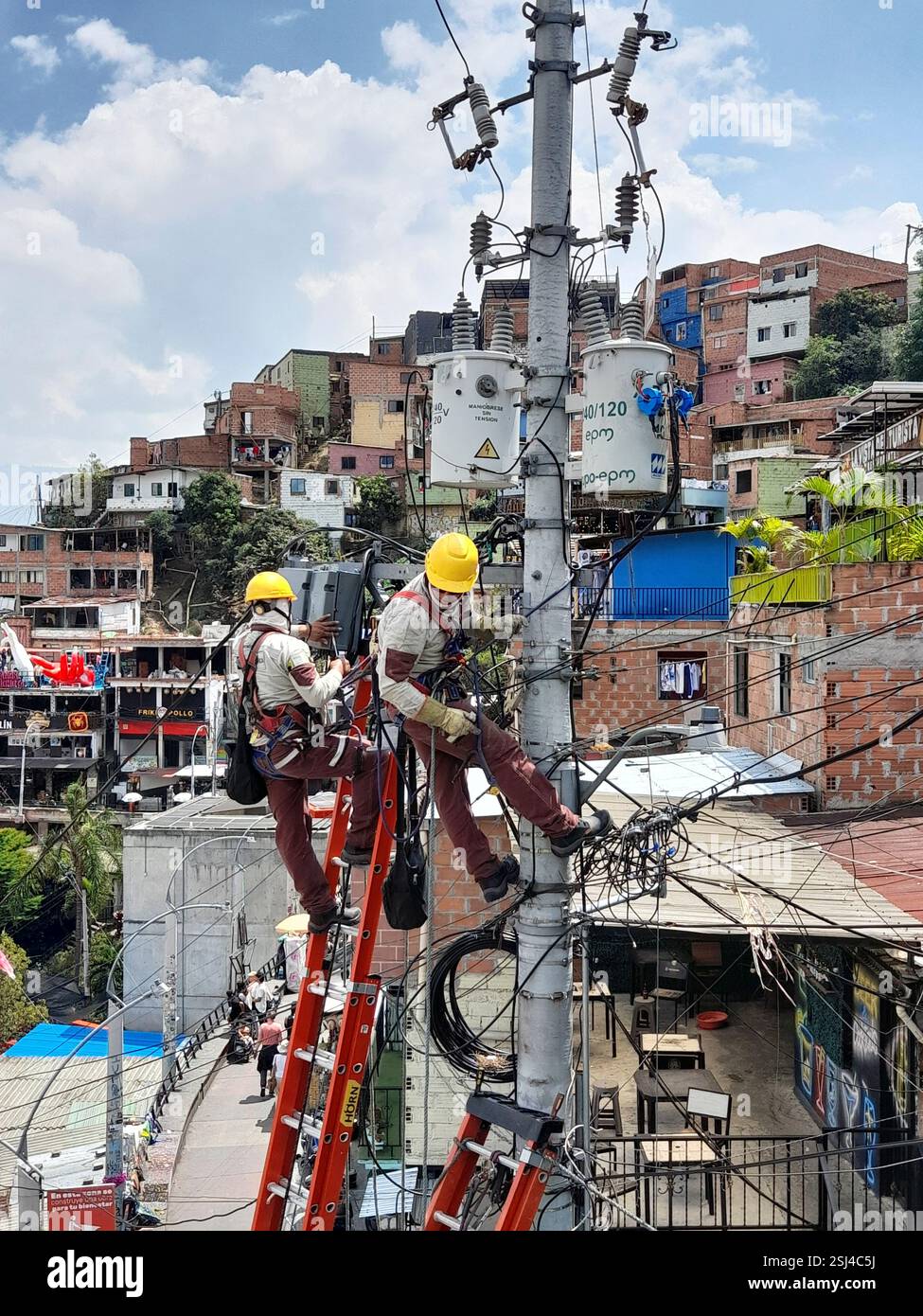 Elektrizitätsarbeiter arbeiten an einem Elektromast in Comuna 13, Medellin, Antioquia, Kolumbien Stockfoto