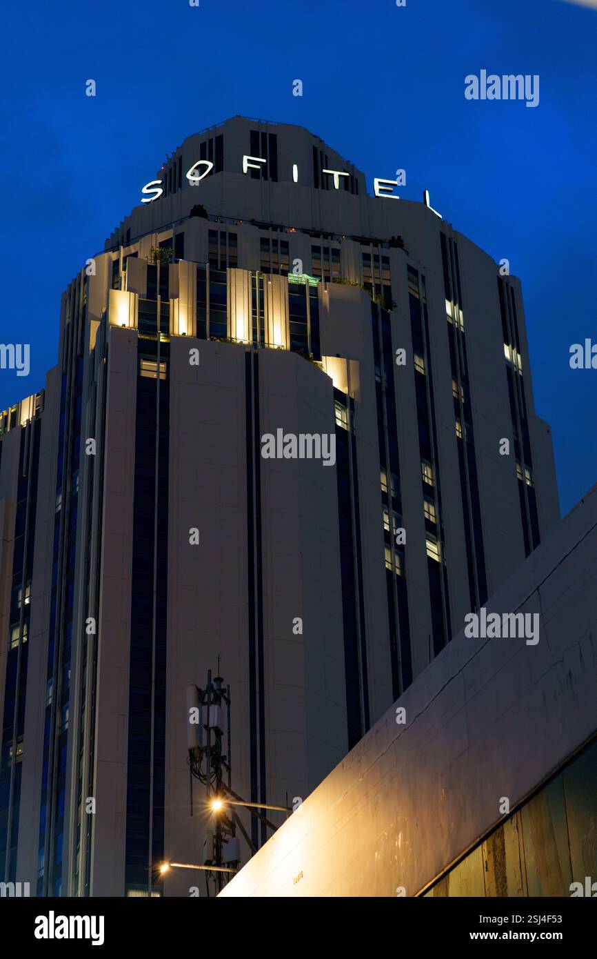 Nächtlicher Blick auf das berühmte Sofitel Hotel an der Sukhumvit Road in Bangkok, Thailand. Das Gebäude steht hoch vor dem tiefblauen Himmel, seiner Fassade Stockfoto