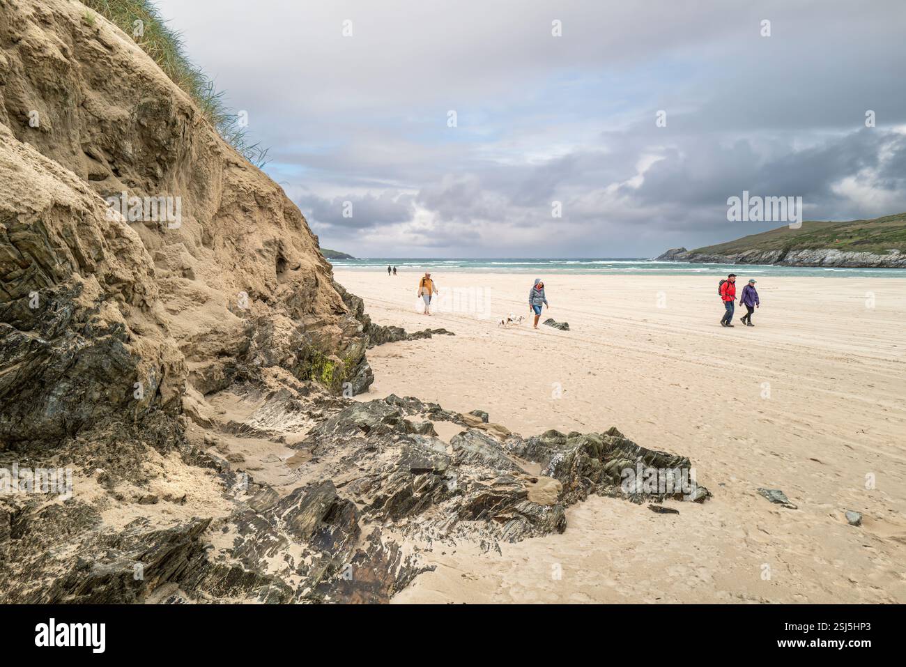 Menschen, die an dem instabilen Sanddünen-System am Crantock Beach in Newquay in Cornwall in Großbritannien vorbeilaufen. Stockfoto