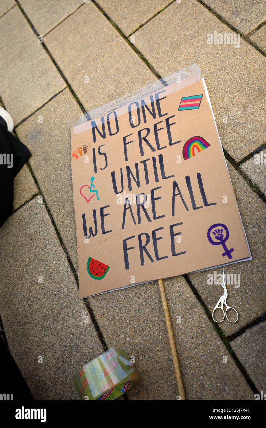 Unter dem Titel nie wieder ist jetzt - Großdemonstration gegen den Rechtsruck in der Gesellschaft - Demoschild: NIEMAND IST FREI BIS WIR ALLE FREI SIND Abbildung: Regenbogen trans Pride Flagge Feminismus Symbol - Deutschland, DE, DEU, Deutschland, Gießen, 08.02.2025: Protestaktion gegen rechte Tendenzen und den gesellschaftlichen Rechtsruck in weiten Teilen der Deutschen Bevölkerung. Ein weiteres aktuelles Thema war die Abstimmung von Union, FDP und AfD im Deutschen Bundestag zur Migrationsdebatte. Die Protestierenden zeigen ihren Unmut gegen den Kanzlerkandidaten der CDU Friedrich Merz auf zahlre Stockfoto