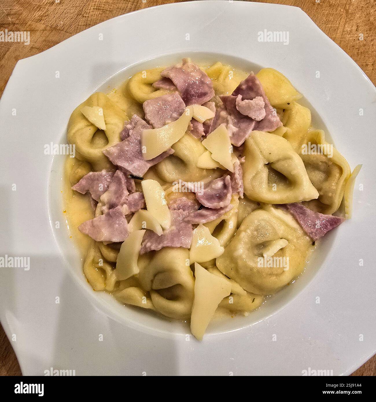 Eine köstliche und köstliche Portion Tortellini, die großzügig mit Schinken und cremigem Käse garniert wird, ideal für Pasta-Liebhaber Stockfoto