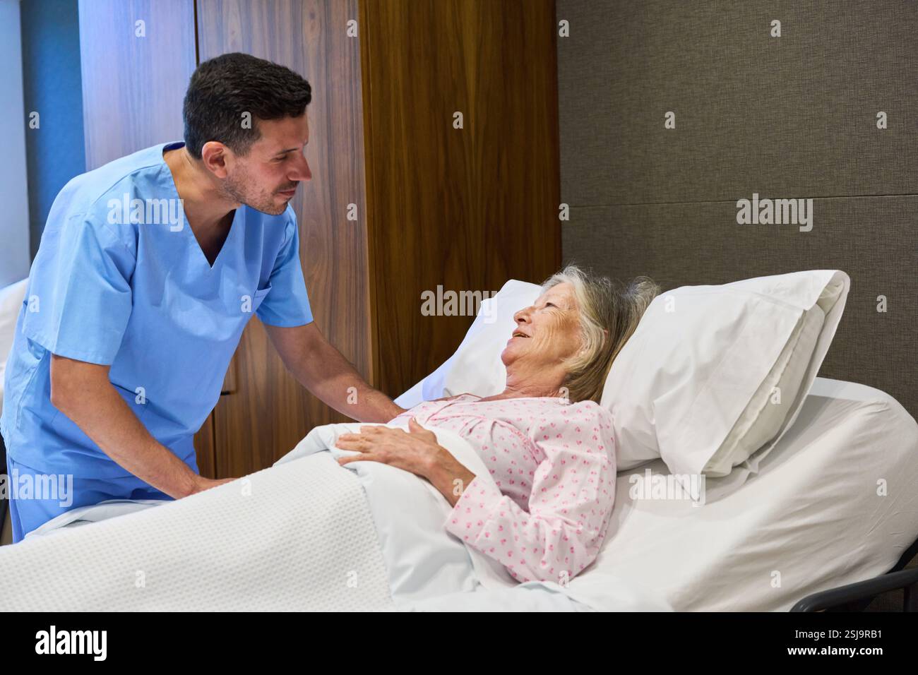 Eine mitfühlende Pflegekraft hilft einer älteren Frau in einer Gesundheitseinrichtung und fördert so die Genesung und das Wohlbefinden. Die Szene zeigt Unterstützung, Empathie, A Stockfoto