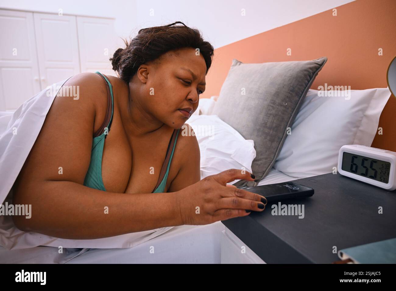 Frau im Bett, die auf das Smartphone schaut Stockfoto