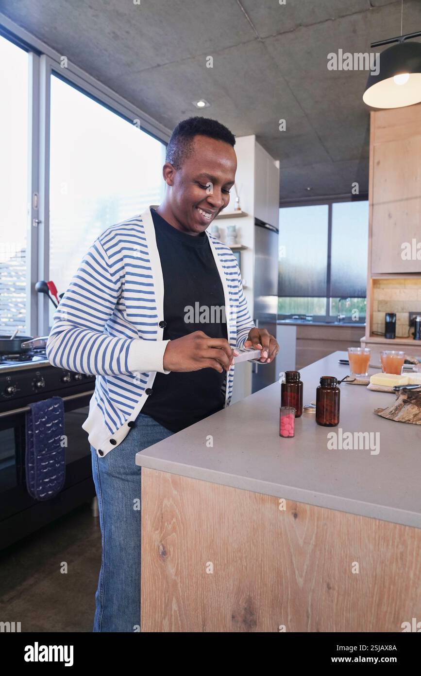 Mann mit Pillen-Organizer in der Küche Stockfoto