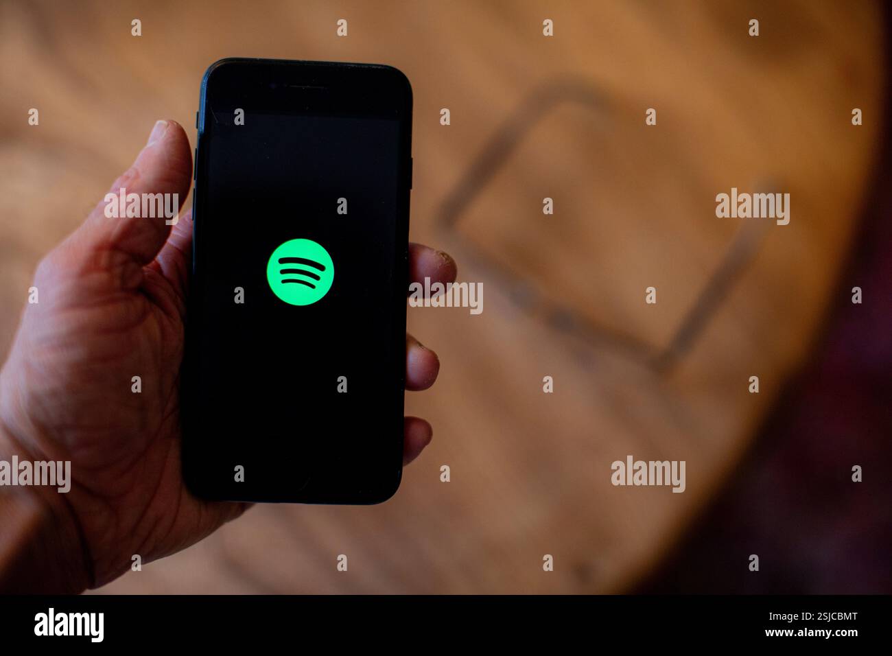 Ein Mobiltelefon wird gehalten und zeigt die Spotify App auf dem Bildschirm an. Foto: SMP News Stockfoto