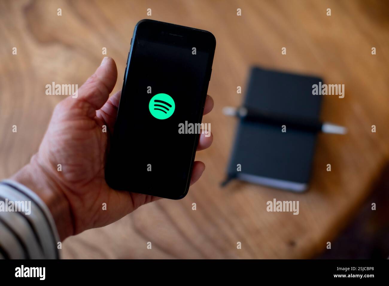 Ein Mobiltelefon wird gehalten und zeigt die Spotify App auf dem Bildschirm an. Foto: SMP News Stockfoto