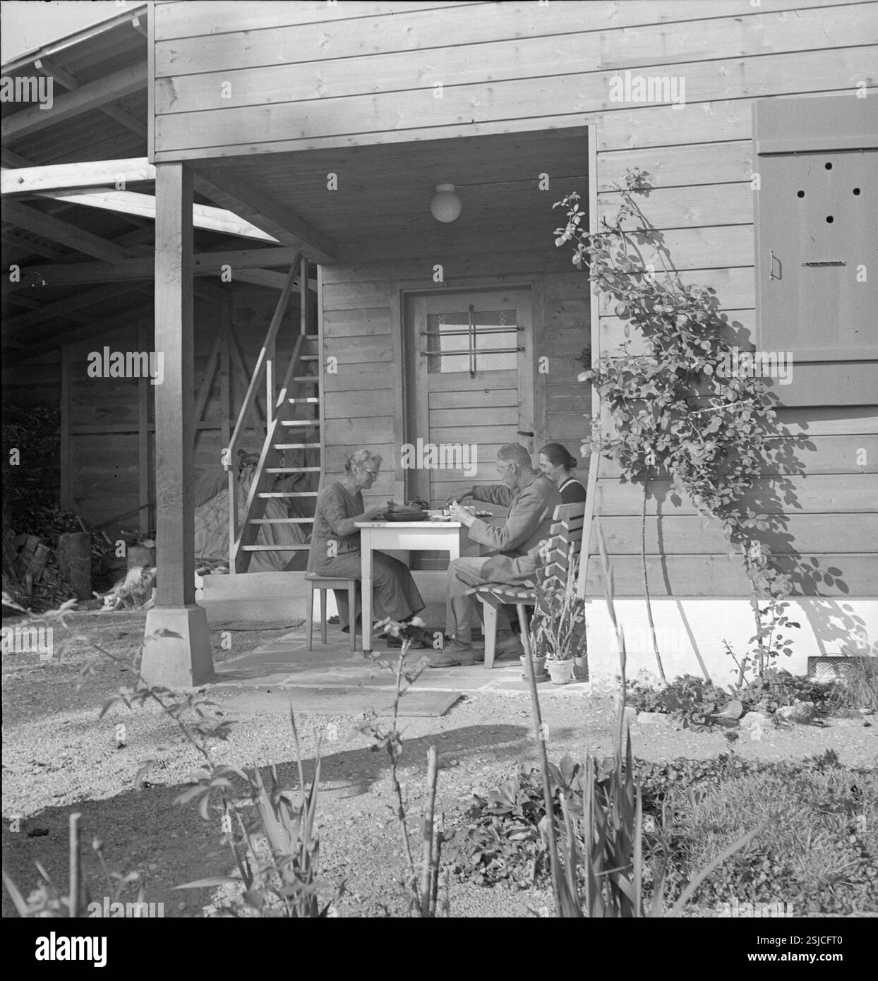 --- Familie beim Essen bei Wohnhaus für Arbeiterfamilie in Laupen; 1939#Laupen: Familie beim Essen am Wohnhaus für Arbeiterfamilien; 1939- RDB VON DUKAS Stockfoto