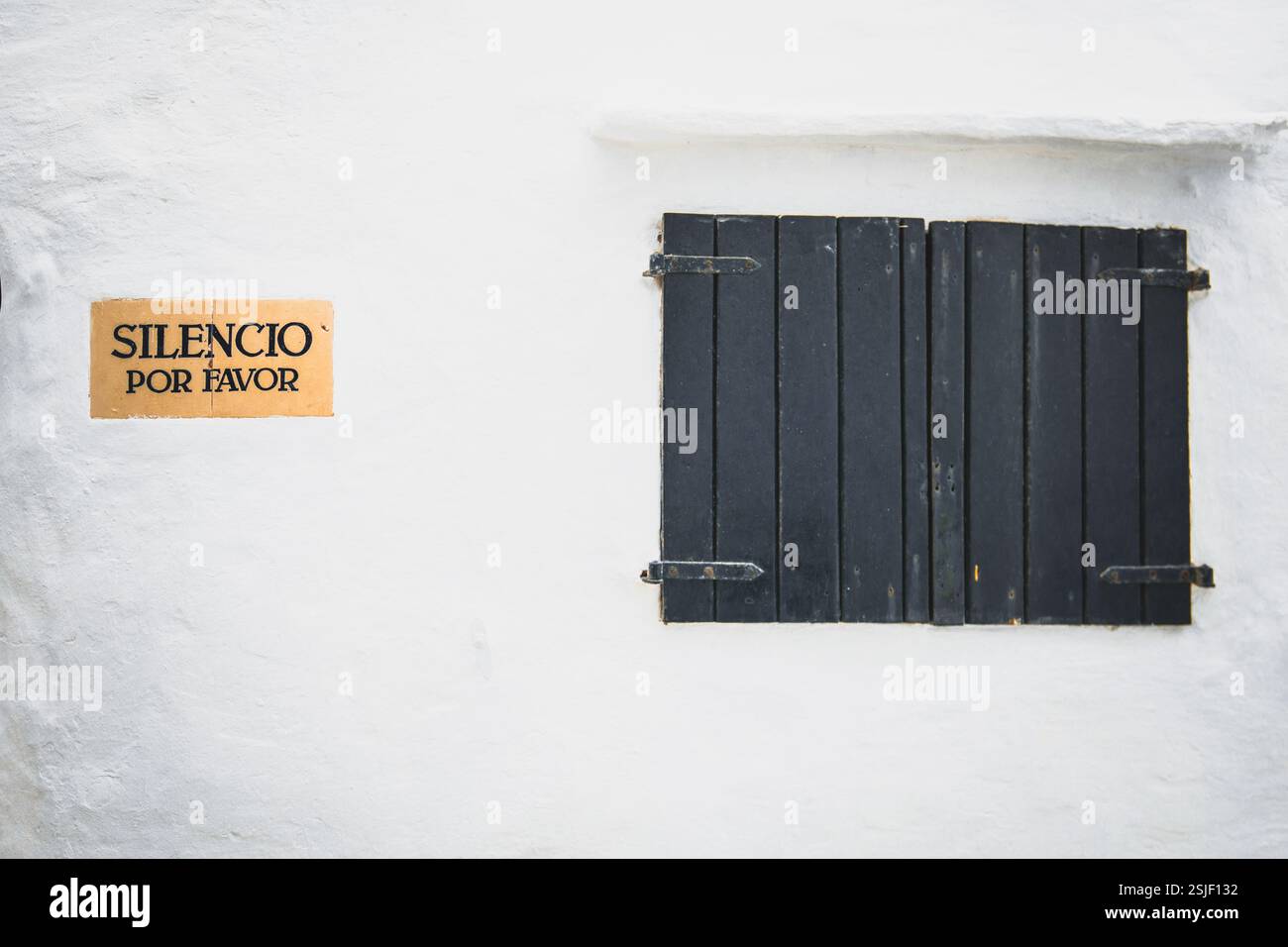 Ein Schild mit der Aufschrift Bitte seien Sie ruhig auf Spanisch (Silencio por favor) an einer weißen Wand eines Gebäudes Stockfoto