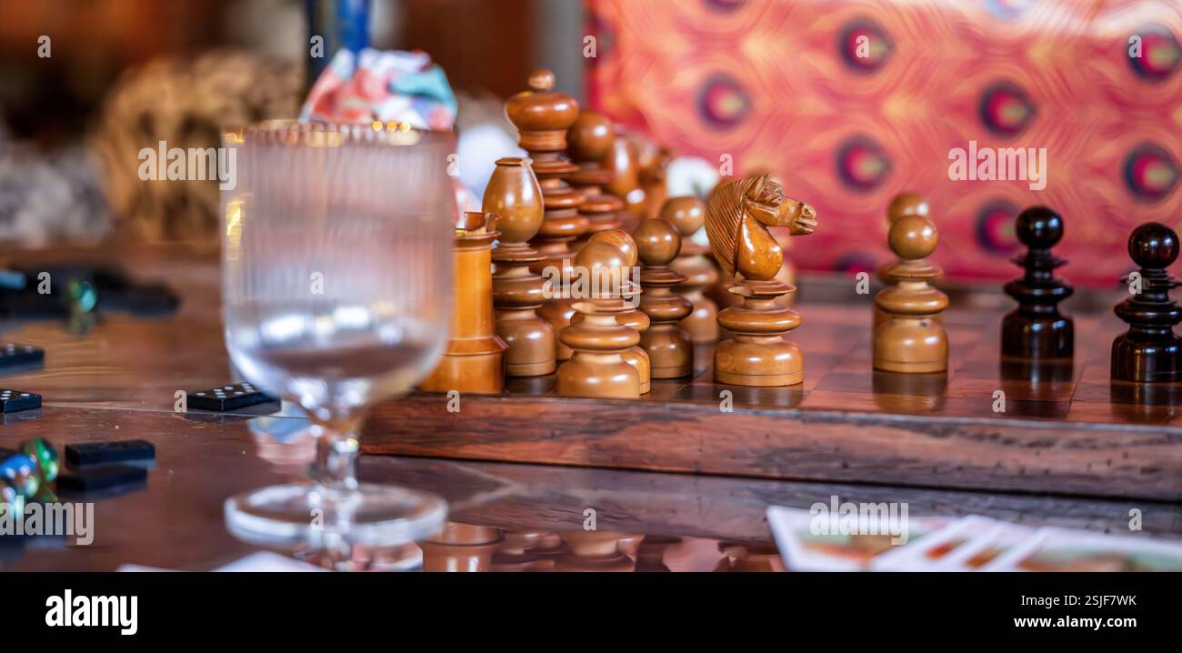 Künstlerisches Schachset mit Dominos, Spielkarten und Gläsern auf einem stilvollen Tisch Stockfoto