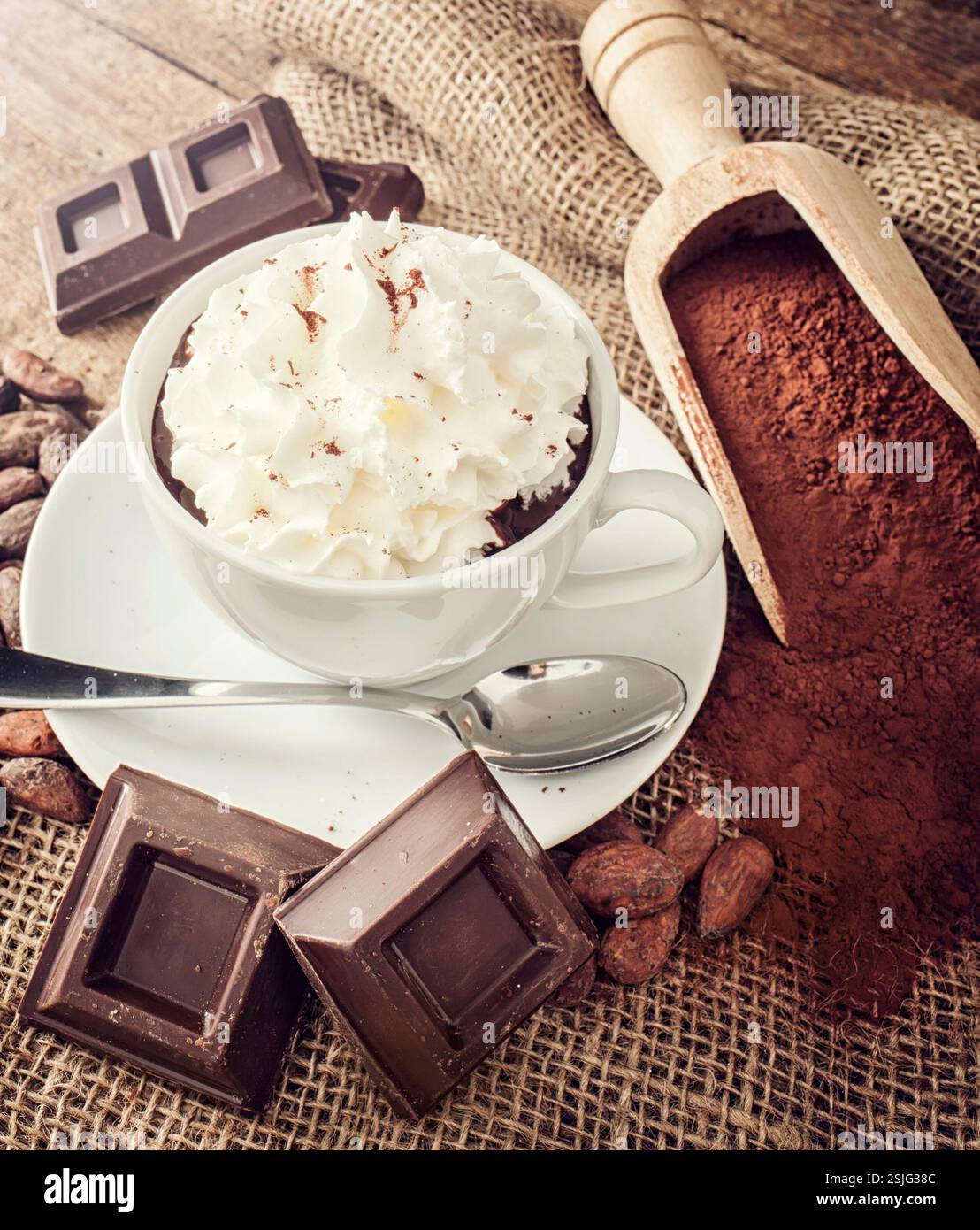 Tasse heiße Schokolade mit Schlagsahne, Kakaopulver, Kakaobohnen und Schokolade. Stockfoto