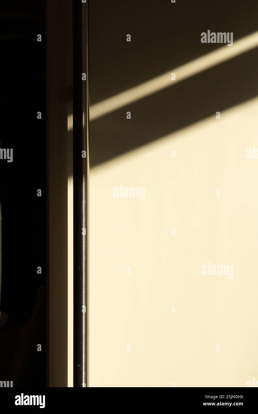 Eine Nahaufnahme eines Schrankgriffs, der von kontrastfarbenem Licht beleuchtet wird und die Form und Textur des Griffs gegen die umgebenden Schatten hervorhebt. Stockfoto