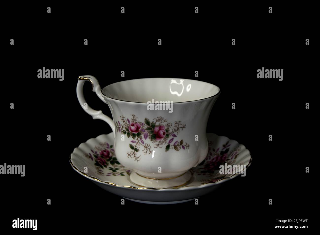 Elegante Vintage Porzellan Teetasse und Untertasse mit zarten Blumenmustern und goldenen Besätzen, isoliert auf schwarzem Hintergrund. Stockfoto
