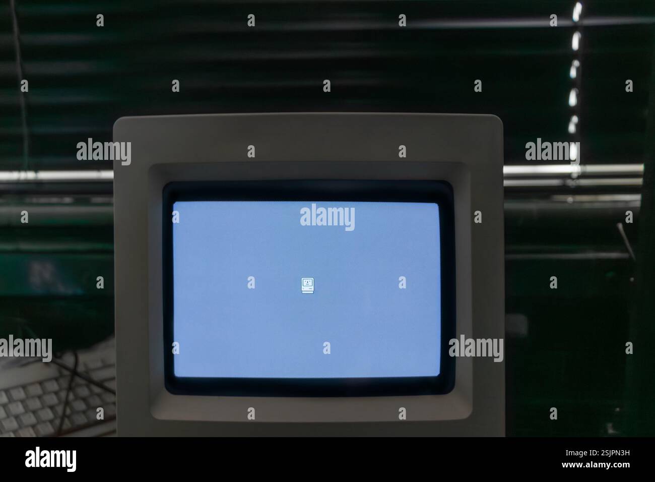 Der Vintage Macintosh-Computerbildschirm zeigt das Smiley-Startlogo in klassischer Schwarz-weiß-Oberfläche Stockfoto