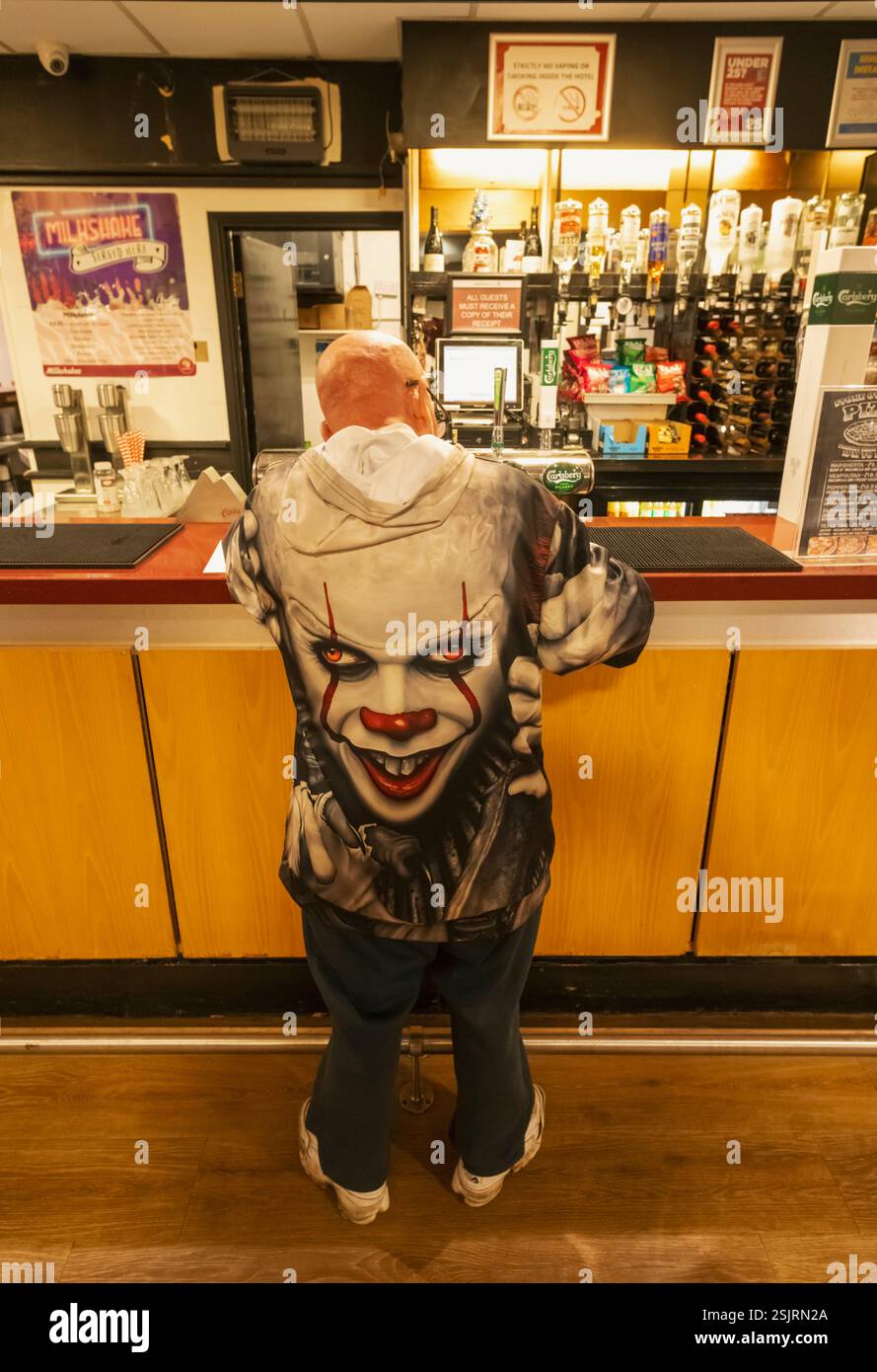 England, Kent, Folkestone, Folkestone Harbour, Britannia Hotelkette The Grand Burstin Hotel, Mann, der an der Bar steht und eine farbenfrohe Joker Jacke trägt Stockfoto
