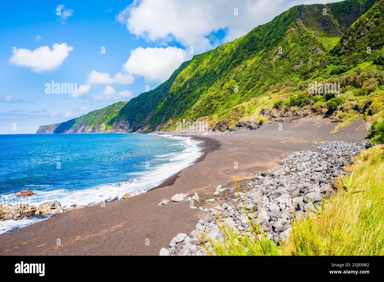 Schwarzer Sand vulkanischer Strand von Faja und grüne tropische Landschaft mit hohen Klippen an der Meeresküste, Faial Insel, Azoren, Portugal Stockfoto