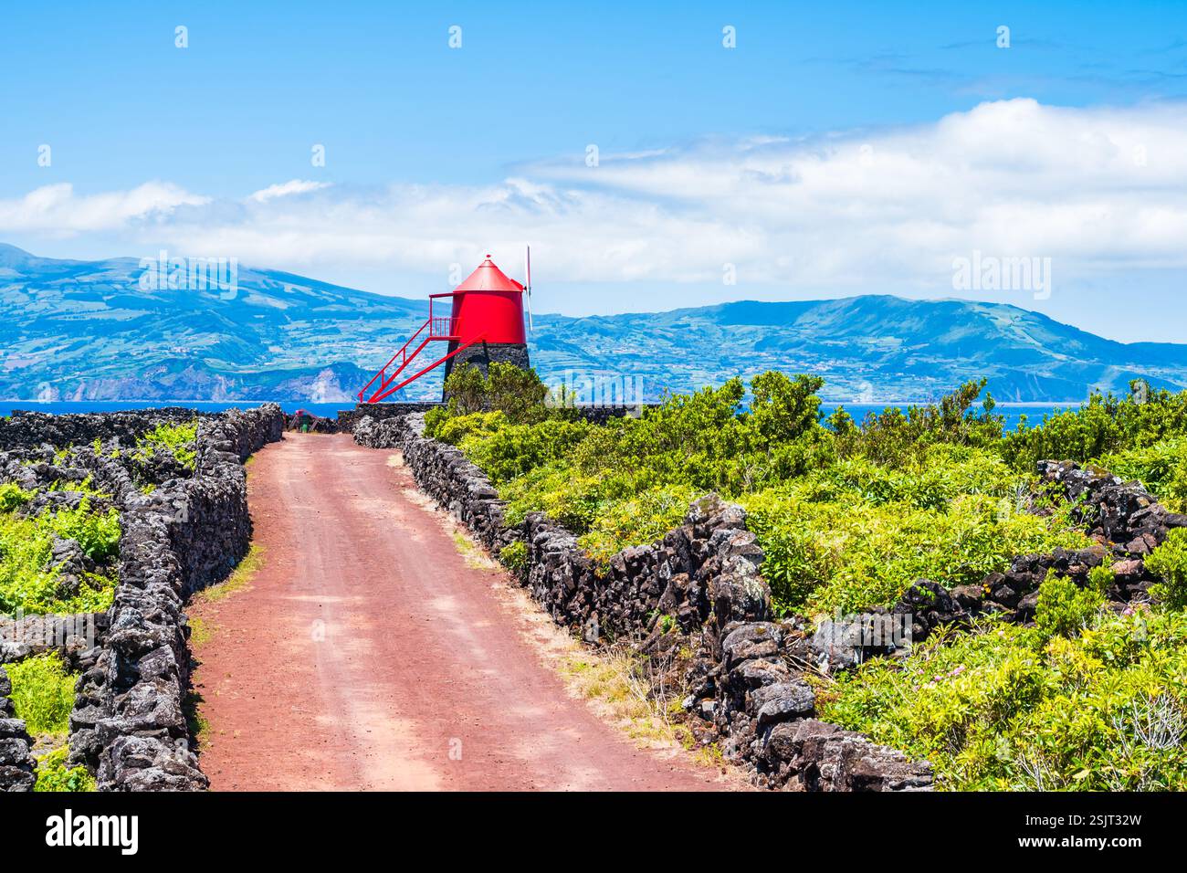 Windmühle in Weinbaukultur zwischen vulkanischen Felsen und unbefestigten Straßen, Insel Pico, Azoren, Portugal Stockfoto