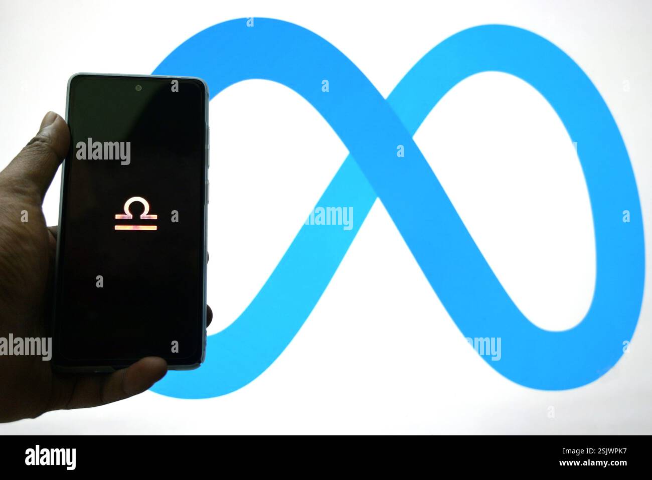 In dieser Fotoabbildung wird das Libra-Logo auf einem Smartphone und das Meta-Logo im Hintergrund angezeigt. Stockfoto